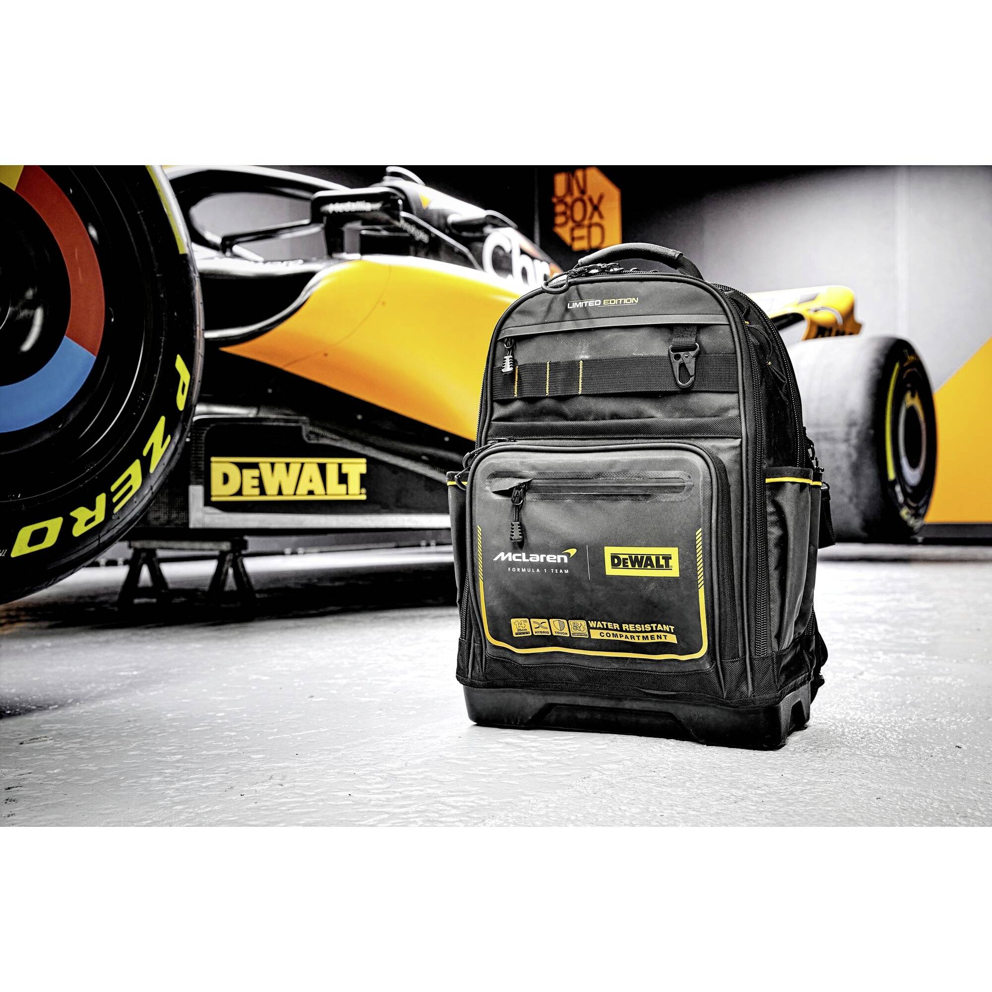 'Een zwarte rugzak met een geel DeWalt-logo staat voor een racewagen met vergelijkbare merkreclame.'