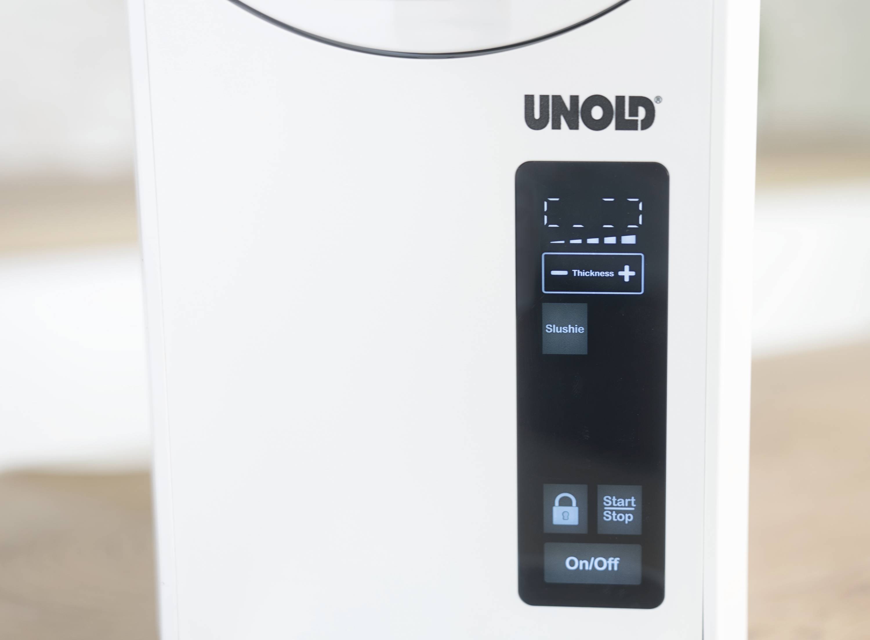 Wit huishoudelijk apparaat van het merk 'Unold'. Digitaal display toont 'Thickness', 'Slushie', 'Start/Stop' en 'On/Off' knoppen.