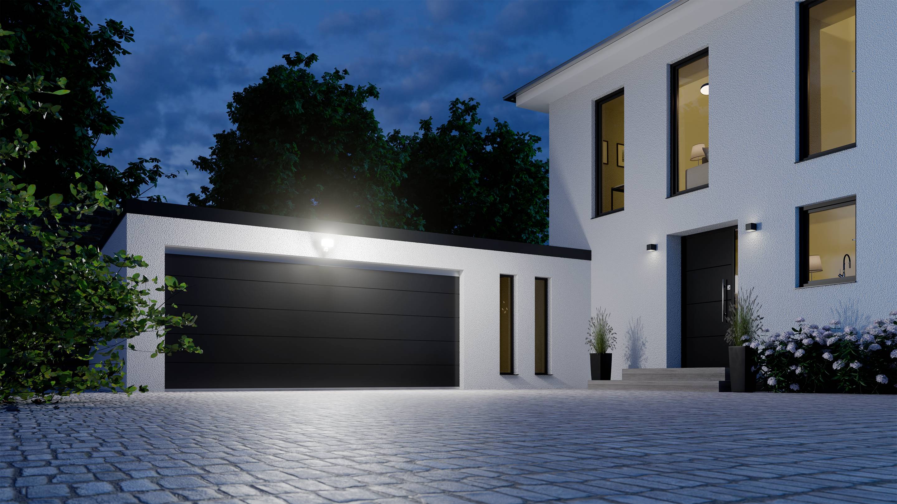 Verlicht, modern huis en garage bij schemering, omgeven door bomen, met een verzorgd stenen pad en bloemen.