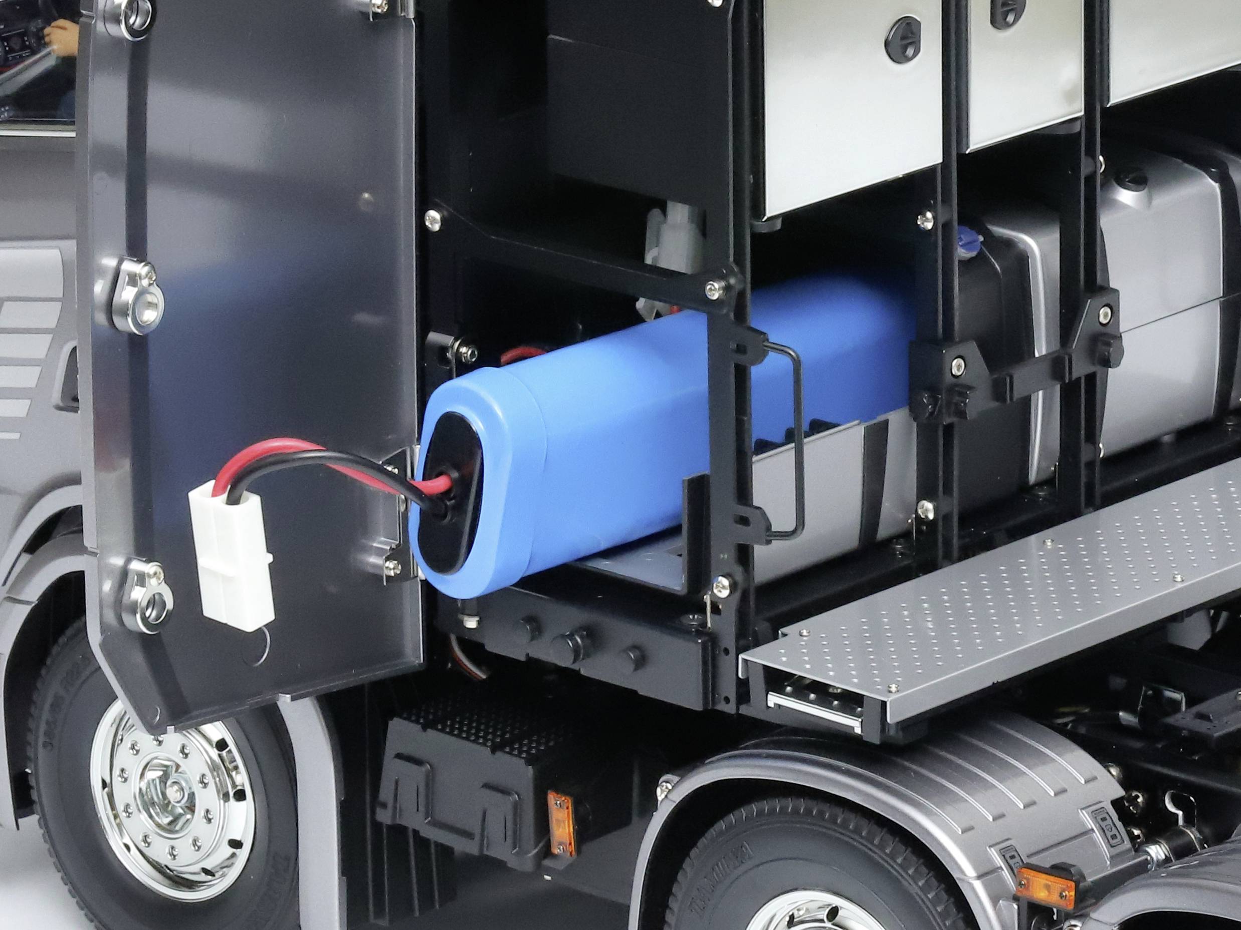 Vrachtwagen met geopende zijdelingse afdekking, toont interne componenten waaronder grote blauwe batterij en bekabeling.