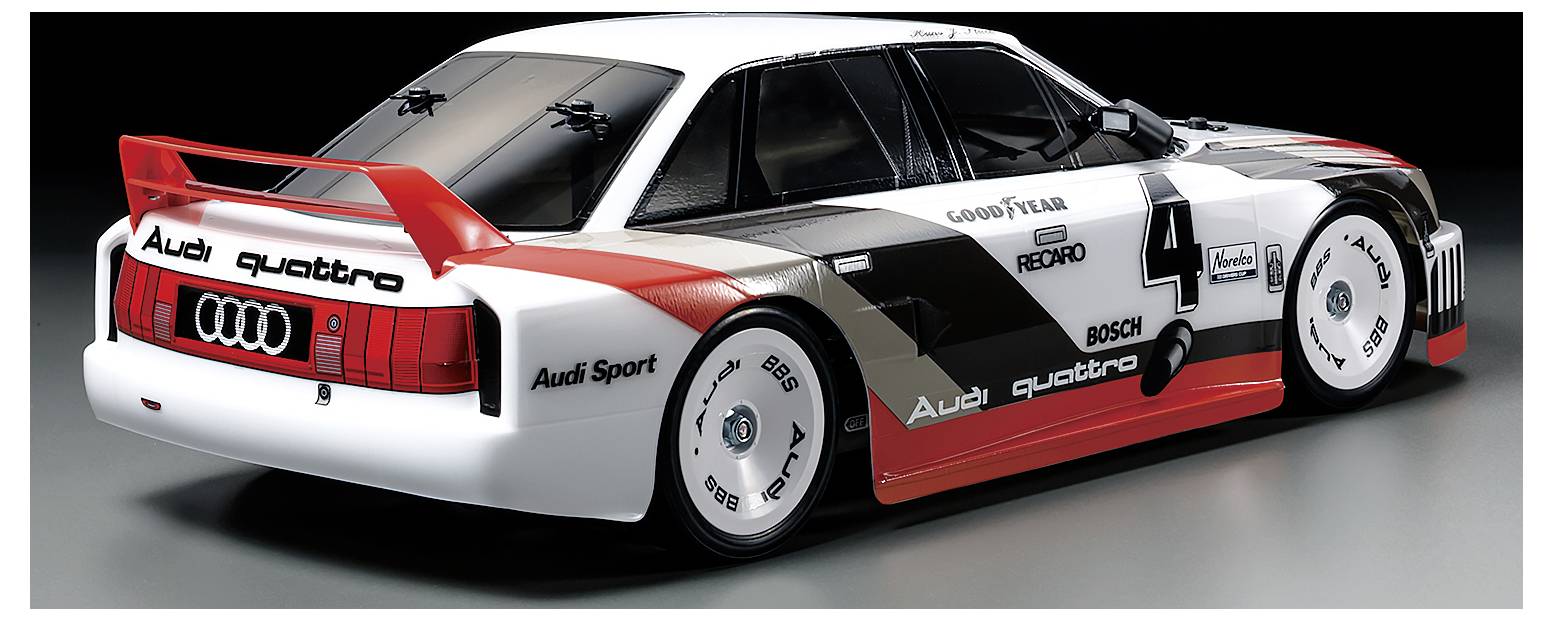 Modelauto van een Audi Quattro met racekleurstelling, nummer 4, op een grijze achtergrond. Sponsormarkeringen duidelijk zichtbaar.