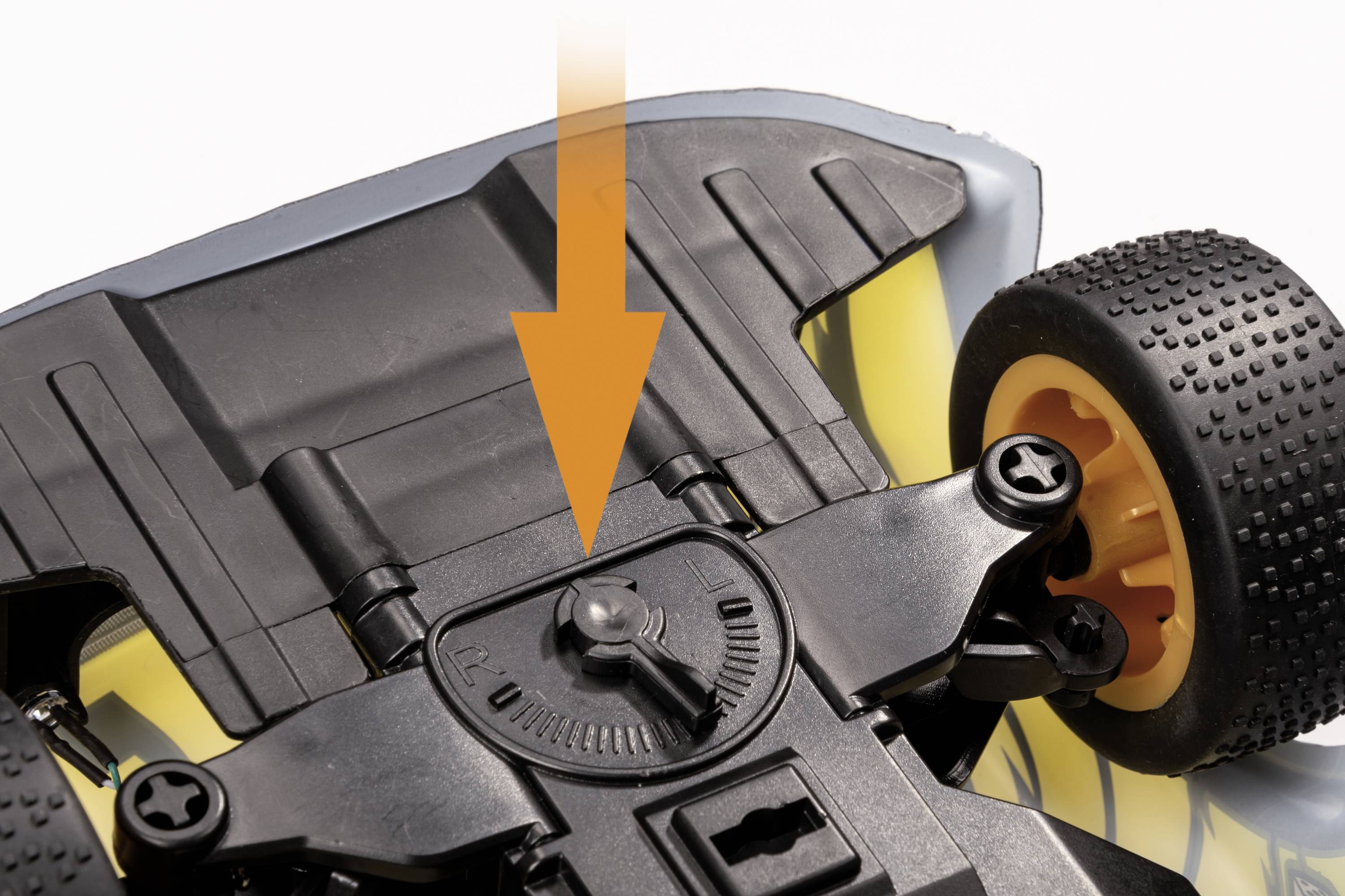 Een onderkant van een speelgoedauto met een gemarkeerde stelschroef die wordt geaccentueerd door een oranje pijl.