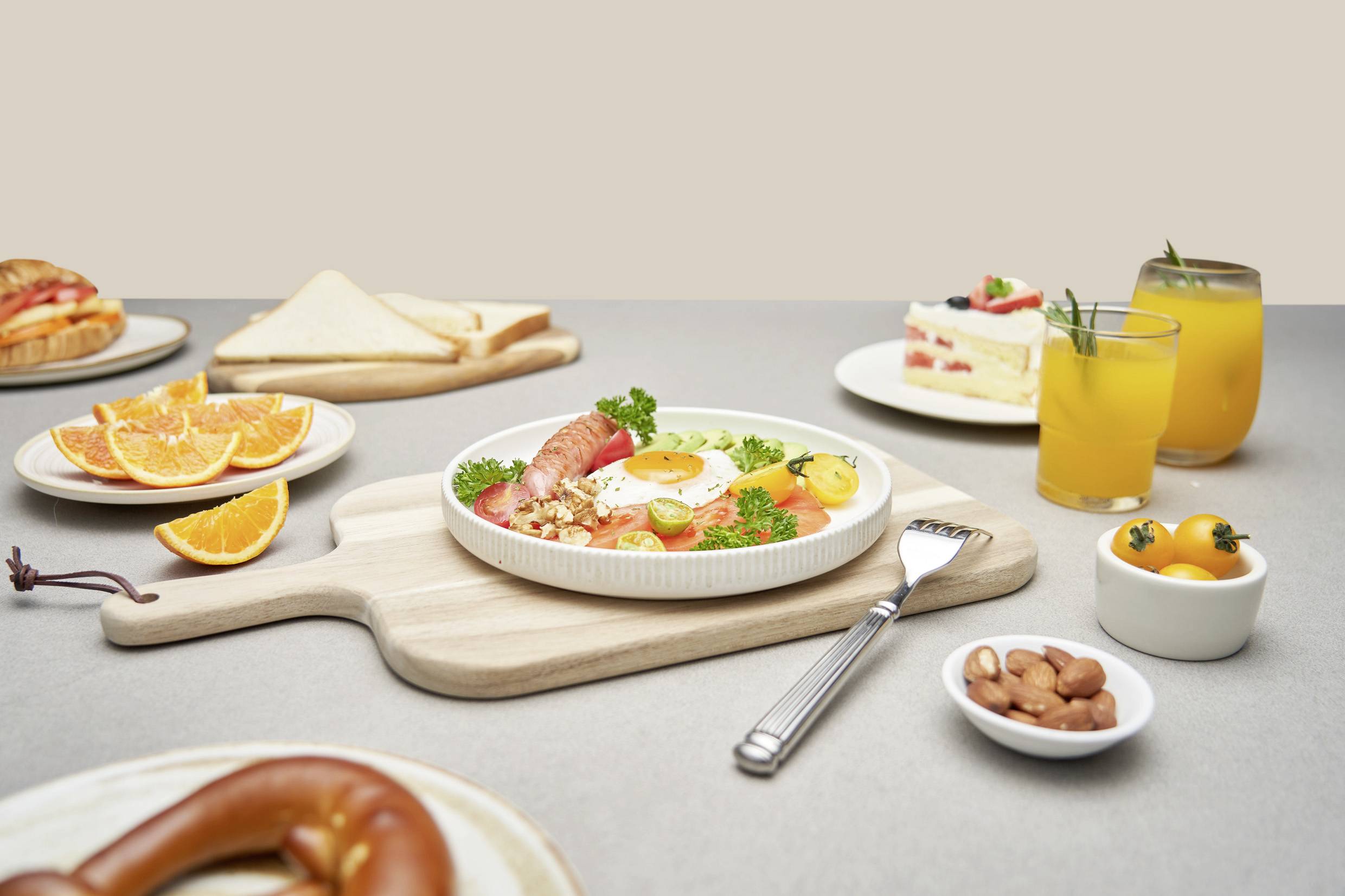 Ontbijttafel met bord: Zalm, ei en groente. Omgeving: Sinaasappelsap, cake, toast, sinaasappelpartjes, pretzel en amandelen.