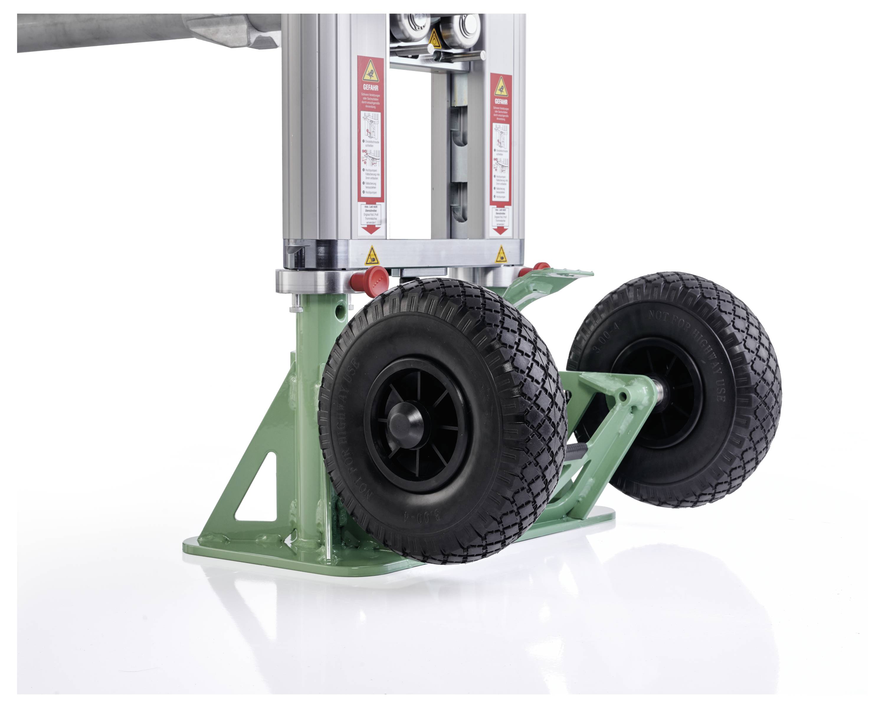 Een groene mechanische hefinrichting met twee zwarte rubberen wielen, die wordt gebruikt voor transport of stabilisatie van apparatuur.