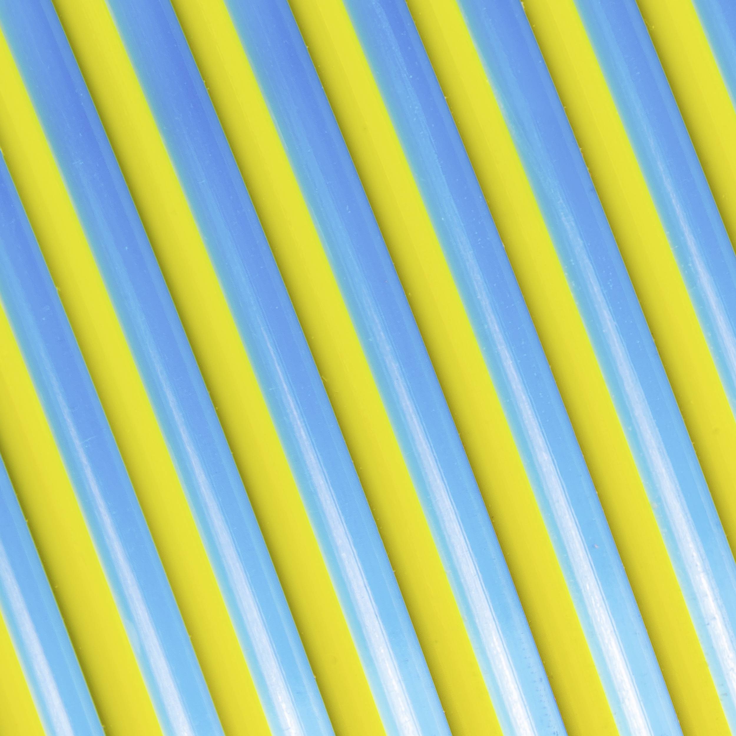 Close-up van kleurrijk gestreepte plastic rietjes in blauw en geel, die parallel lopen.
