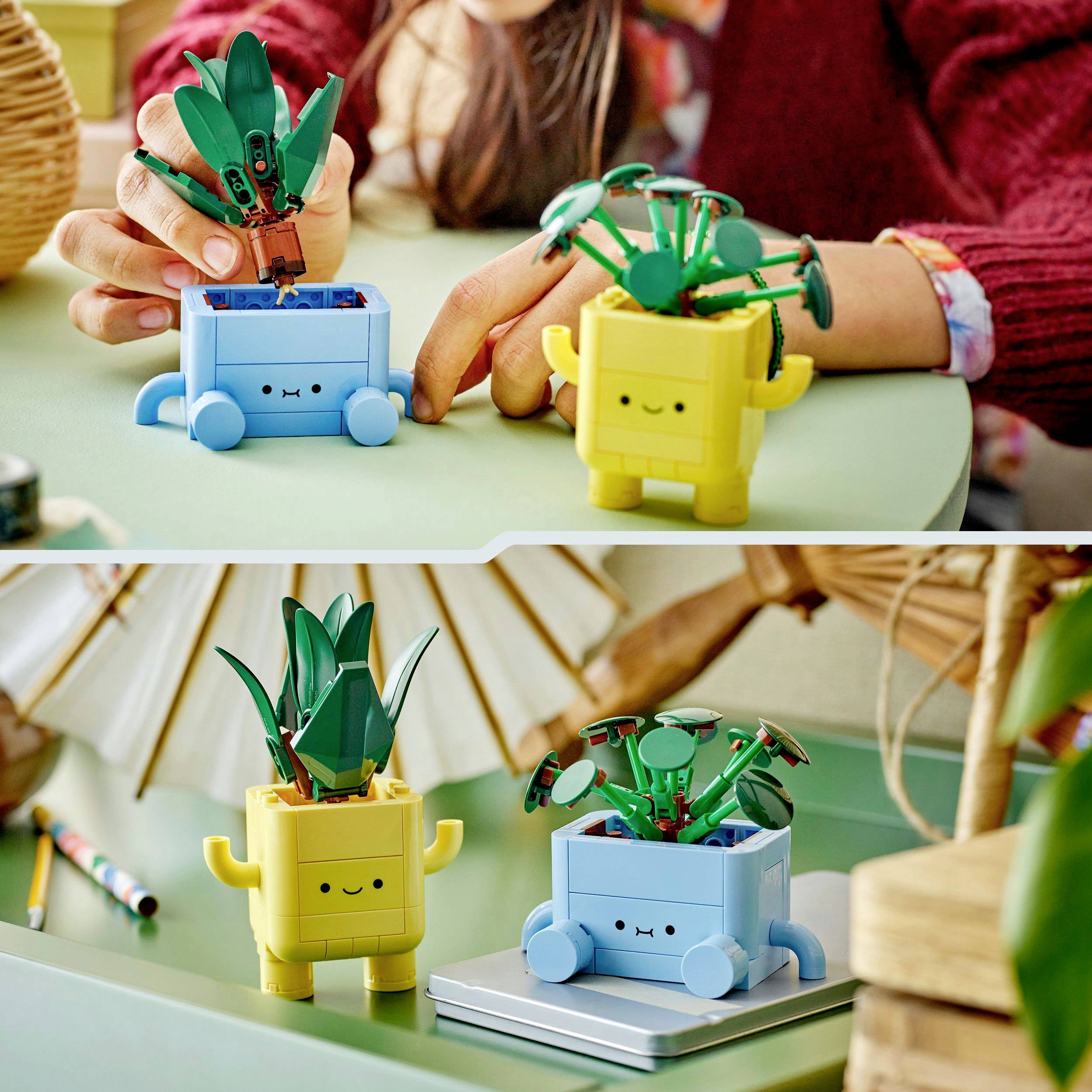 Twee speelfiguren in de vorm van kleine robotplanten op een tafel, een in geel en een in blauw, met een kind dat naar ze kijkt.