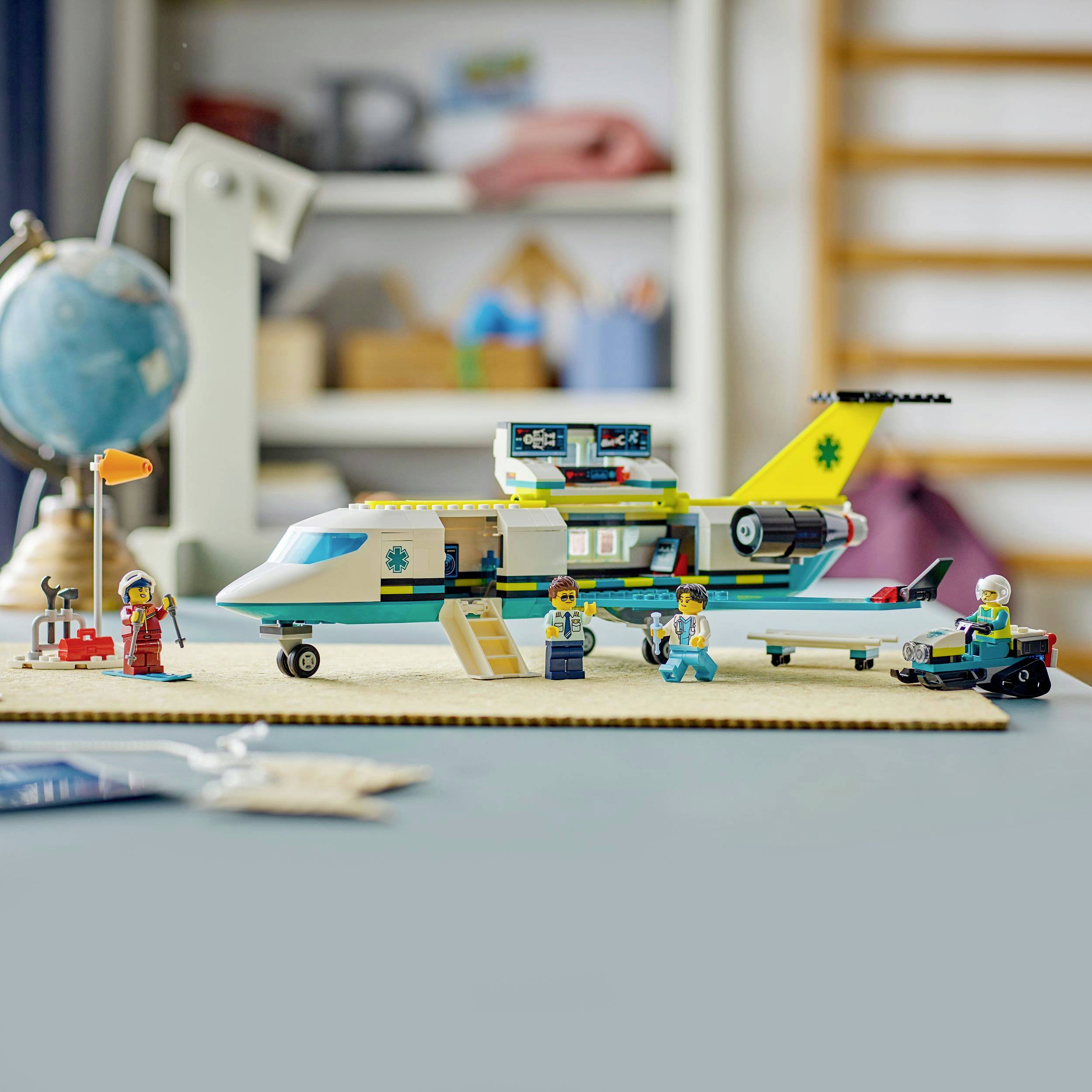 Een LEGO-reddingshelikopter met figuren in werkkleding op de voorgrond. Op de achtergrond zijn onscherp voorwerpen op planken zichtbaar.