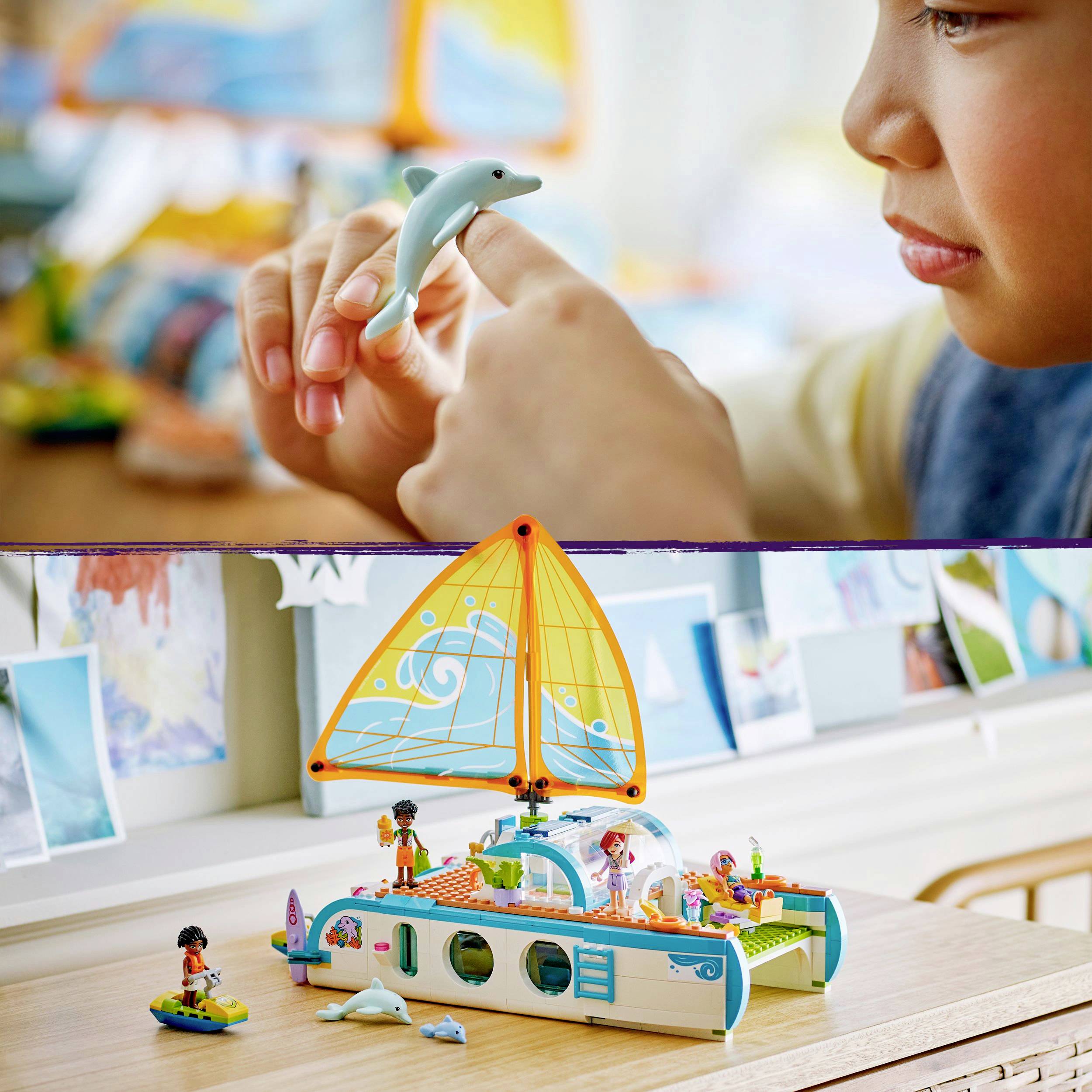 Een kind speelt met een kleine plastic dolfijn. Op de achtergrond is een kleurrijk speelgoedschip met figuren te zien.