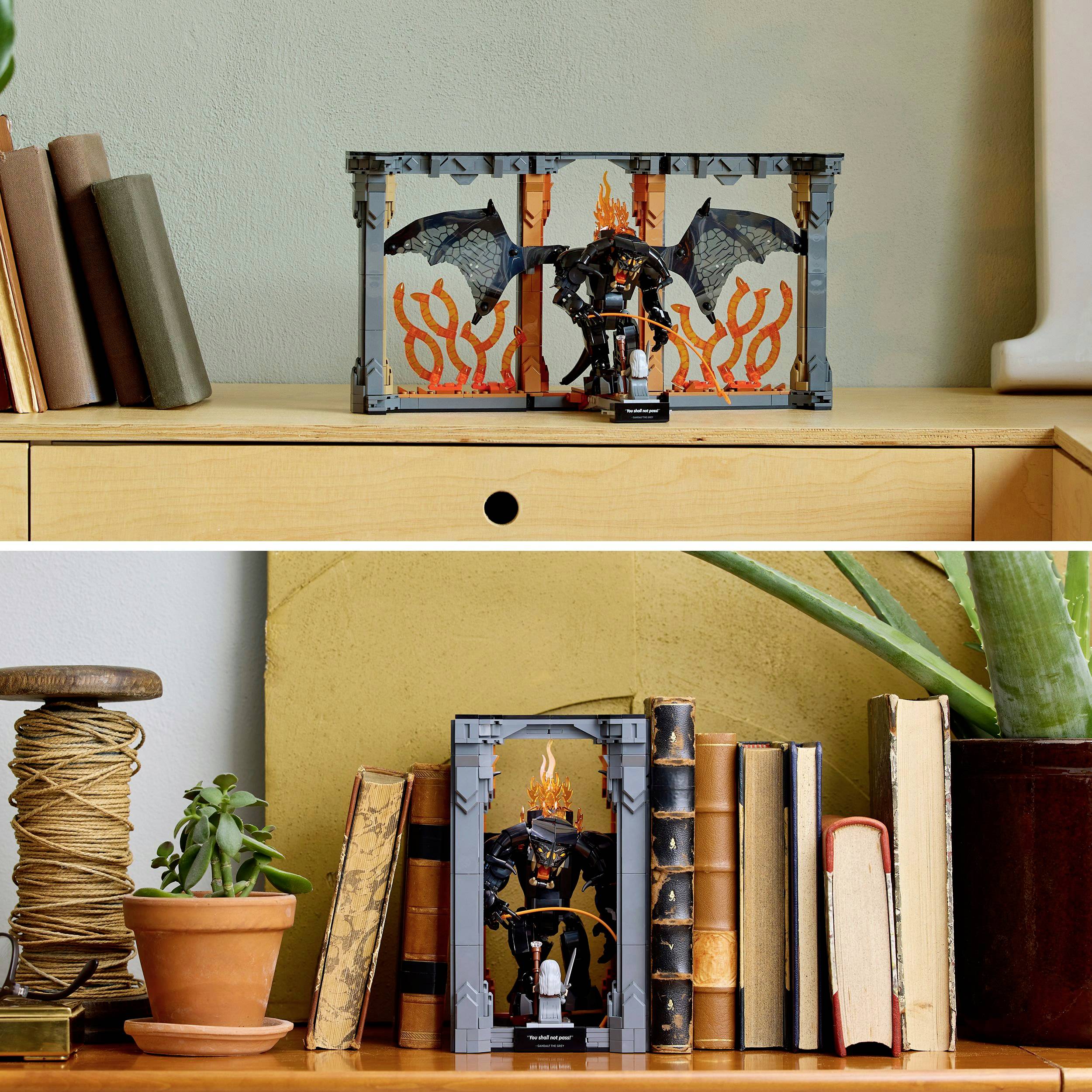 Een diorama op een ladekast toont een figuur van een zwart monster met vleugels voor vlammen, omringd door boeken en planten.