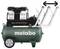 Een groene Metabo-compressor met een zwarte motor, model 'Basic 270-50 OF Silent', met aangebrachte hendels die de bewegingsrichting aangeven.