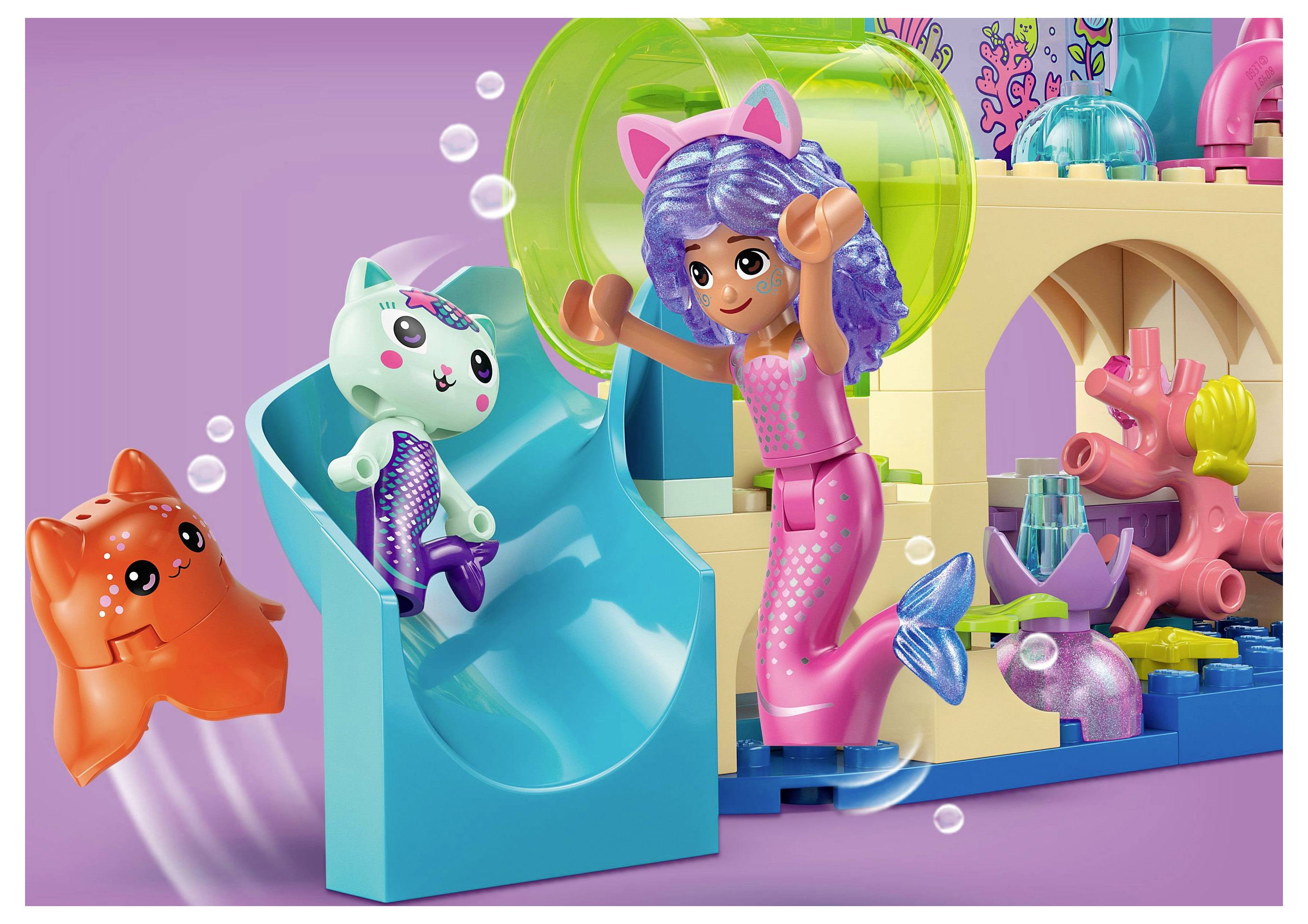 Drie kleurrijke speelgoedfiguren spelen op een waterglijbaan: een zeemeermin met paars haar, een kat in een paars kostuum, en een oranje krab.