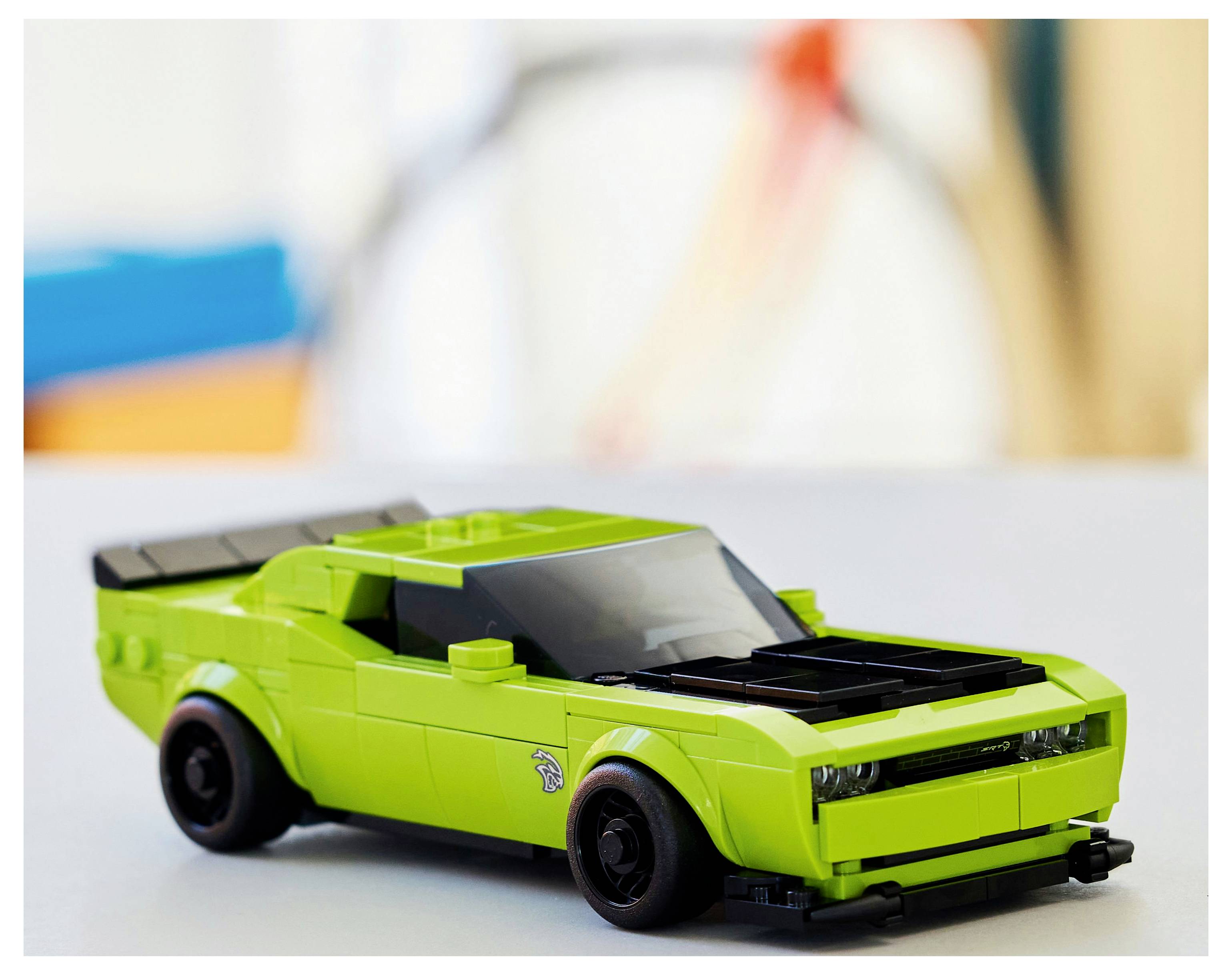 Een felgroene speelgoedauto, gelijkend op een sportwagen, met zwarte wielen en details, staat op een neutrale achtergrond.