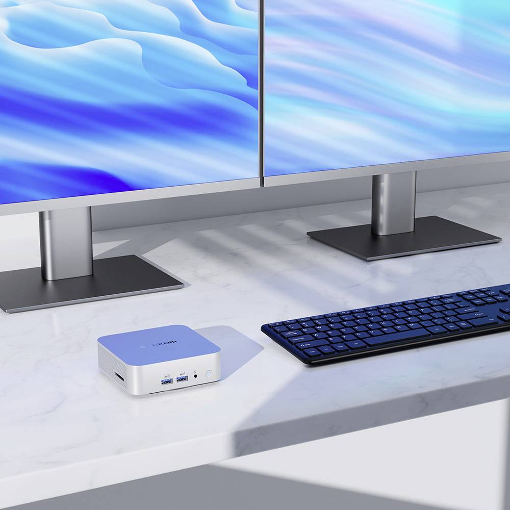 Mini-pc op een bureau met twee monitoren en een toetsenbord. Monitors tonen blauwe golfpatronen.