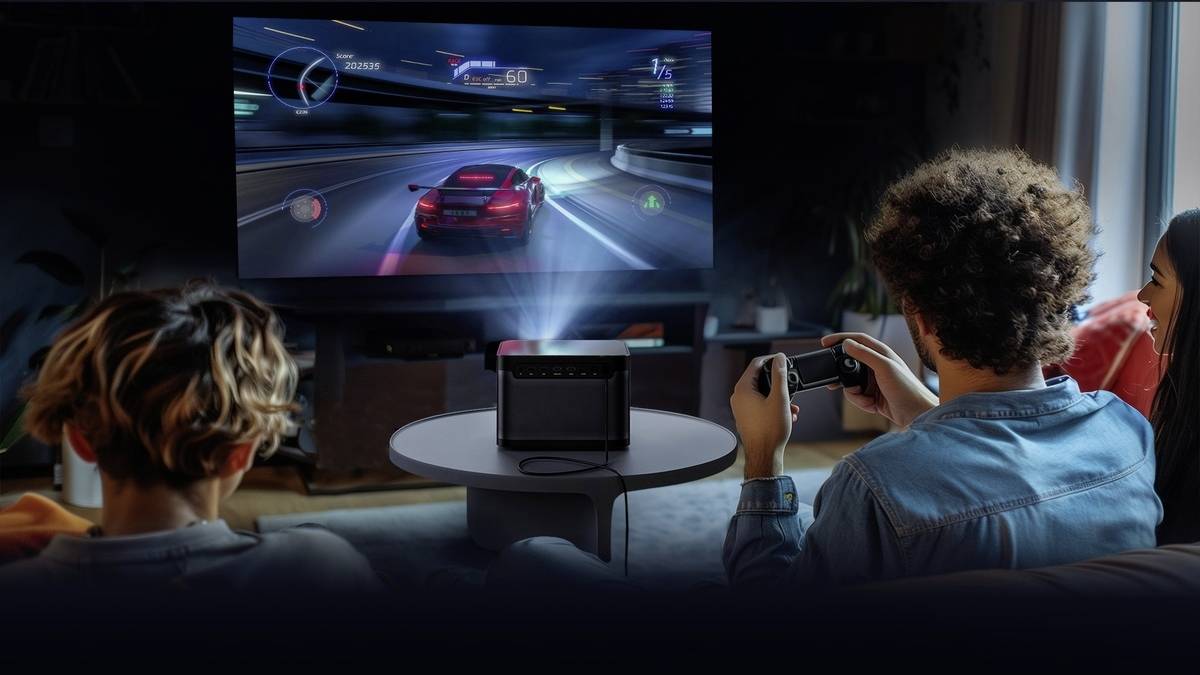 Twee personen spelen een racespel op een groot scherm in de woonkamer. Een projector toont het spel op de televisie.