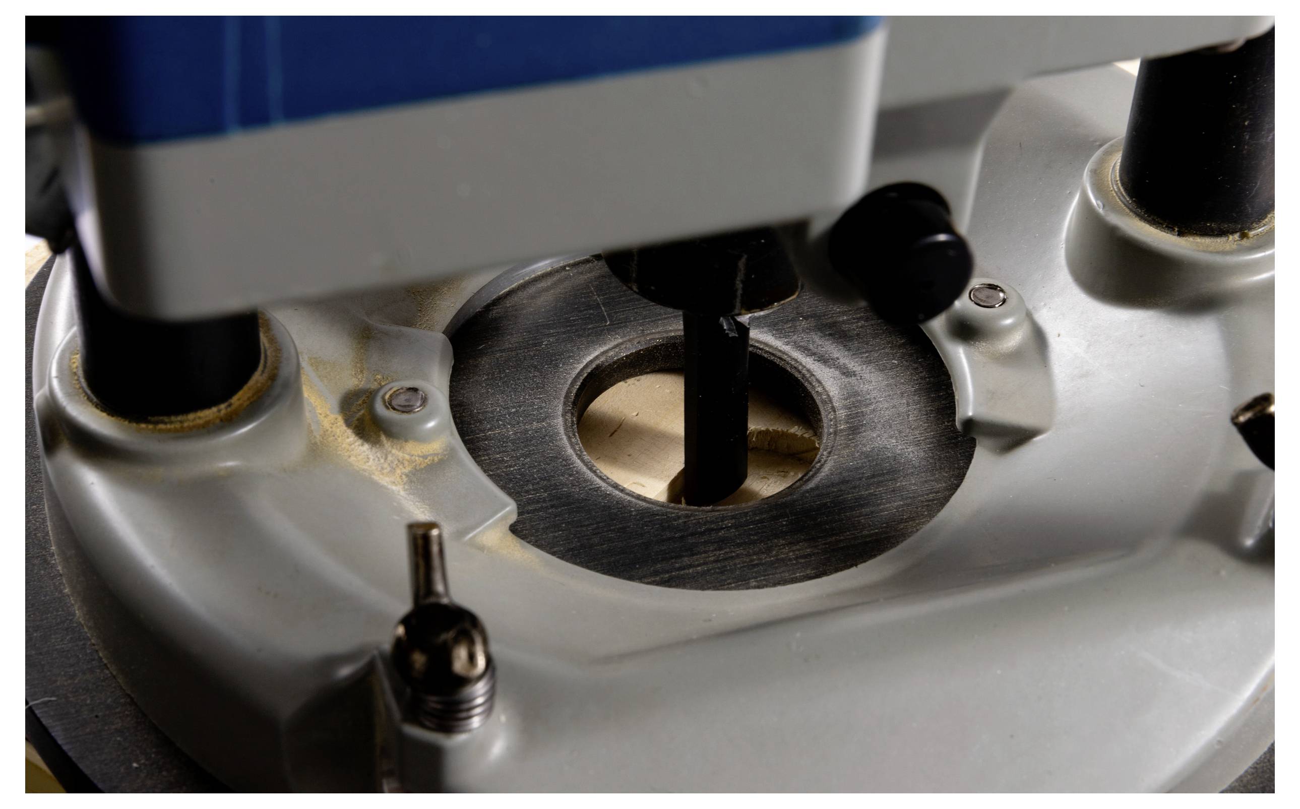 Een close-up van een routeergereedschap waarbij de draaiende frees, omhuld door een behuizing van metaal en plastic, zichtbaar is, gebruikt voor het vormen en snijden van materialen.