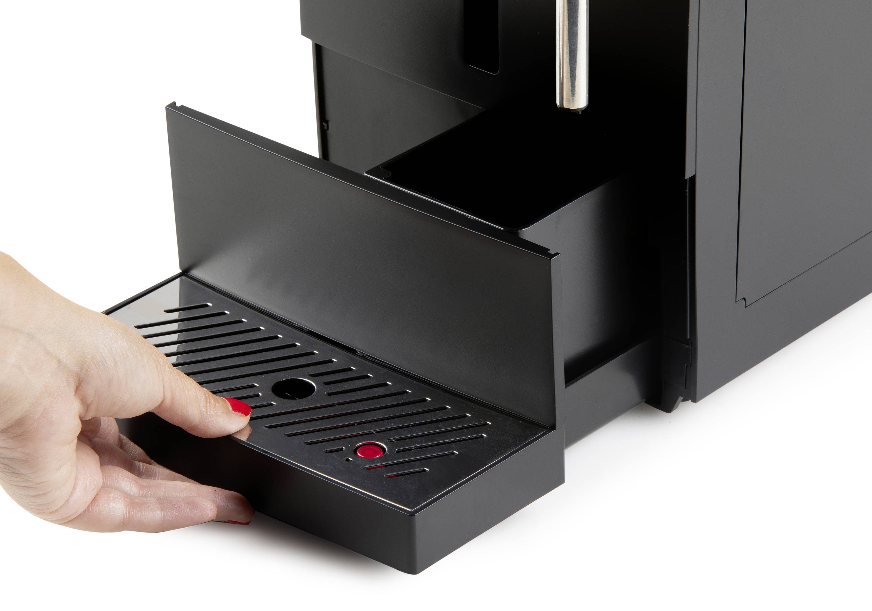 Een persoon haalt de lekbak van een zwarte koffiemachine eruit om deze te legen of schoon te maken.