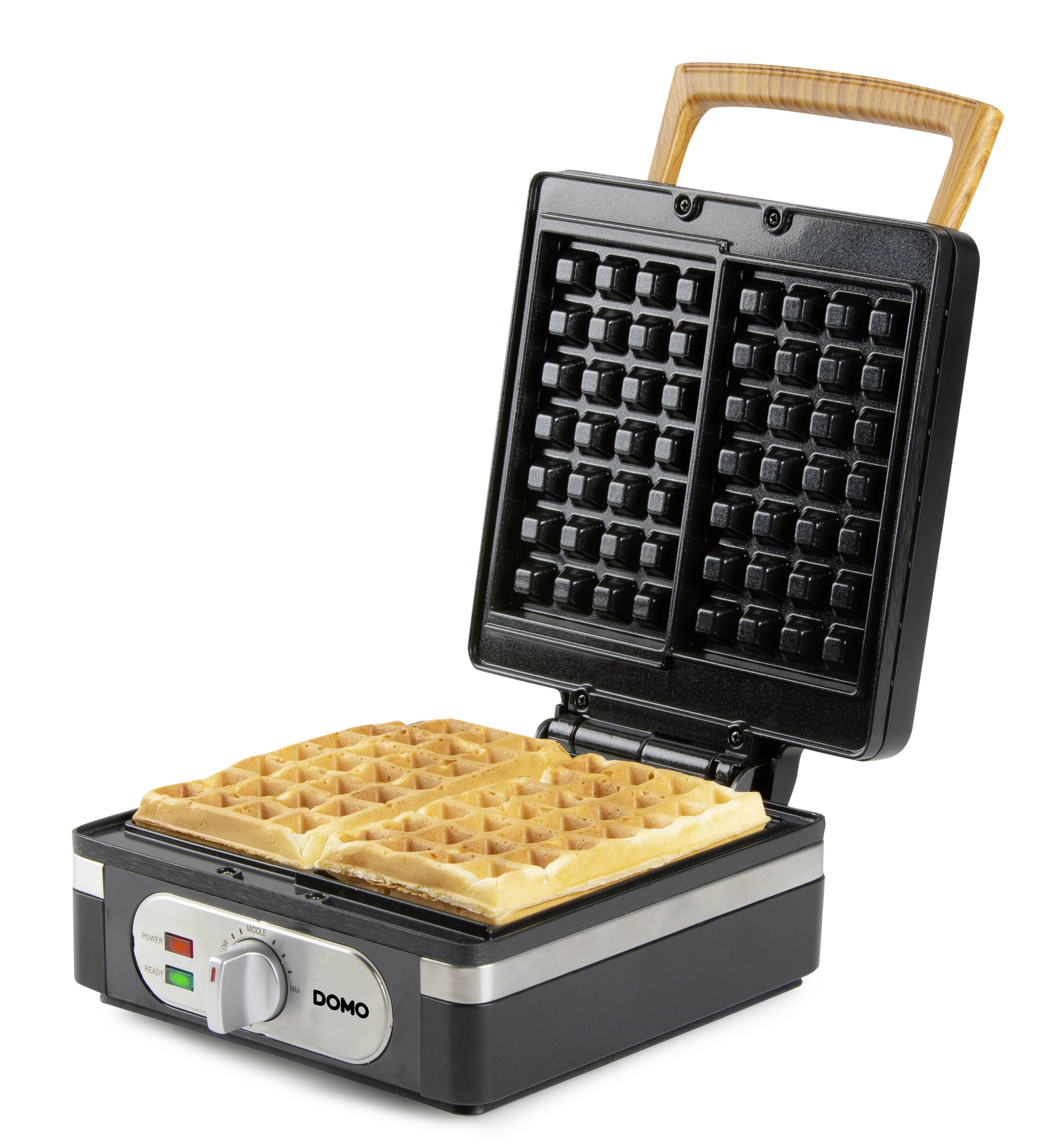 Het beeld toont een geopend wafelijzer met twee vers gebakken, goudbruine wafels. Het apparaat is gemaakt van roestvrij staal met een houten handvat.