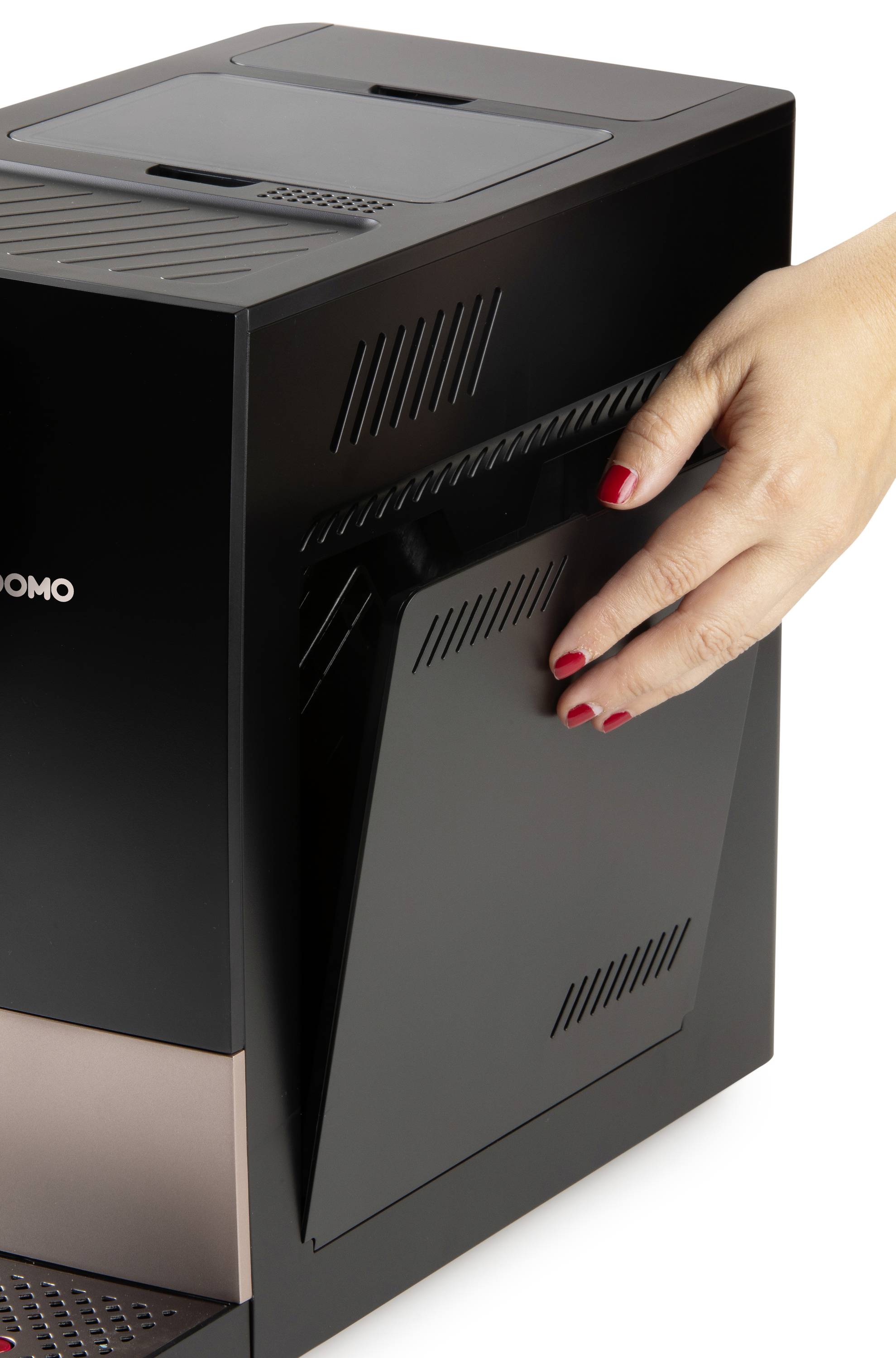 Een hand met rode nagels opent de zijklep van een zwarte koffieautomaat.