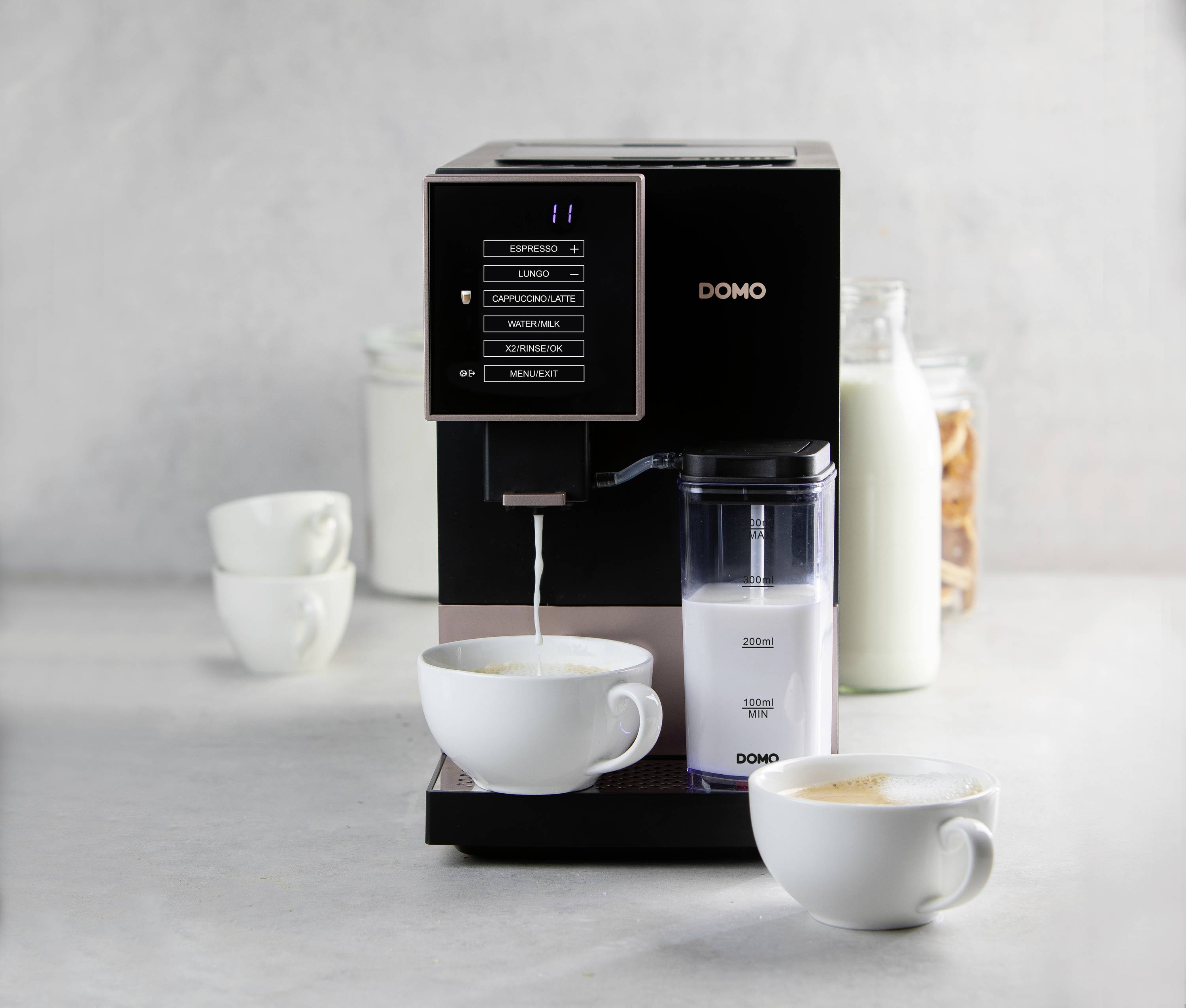 Een koffiemachine zet koffie in een kopje. Naast de machine zijn melk en koffiecups te zien.