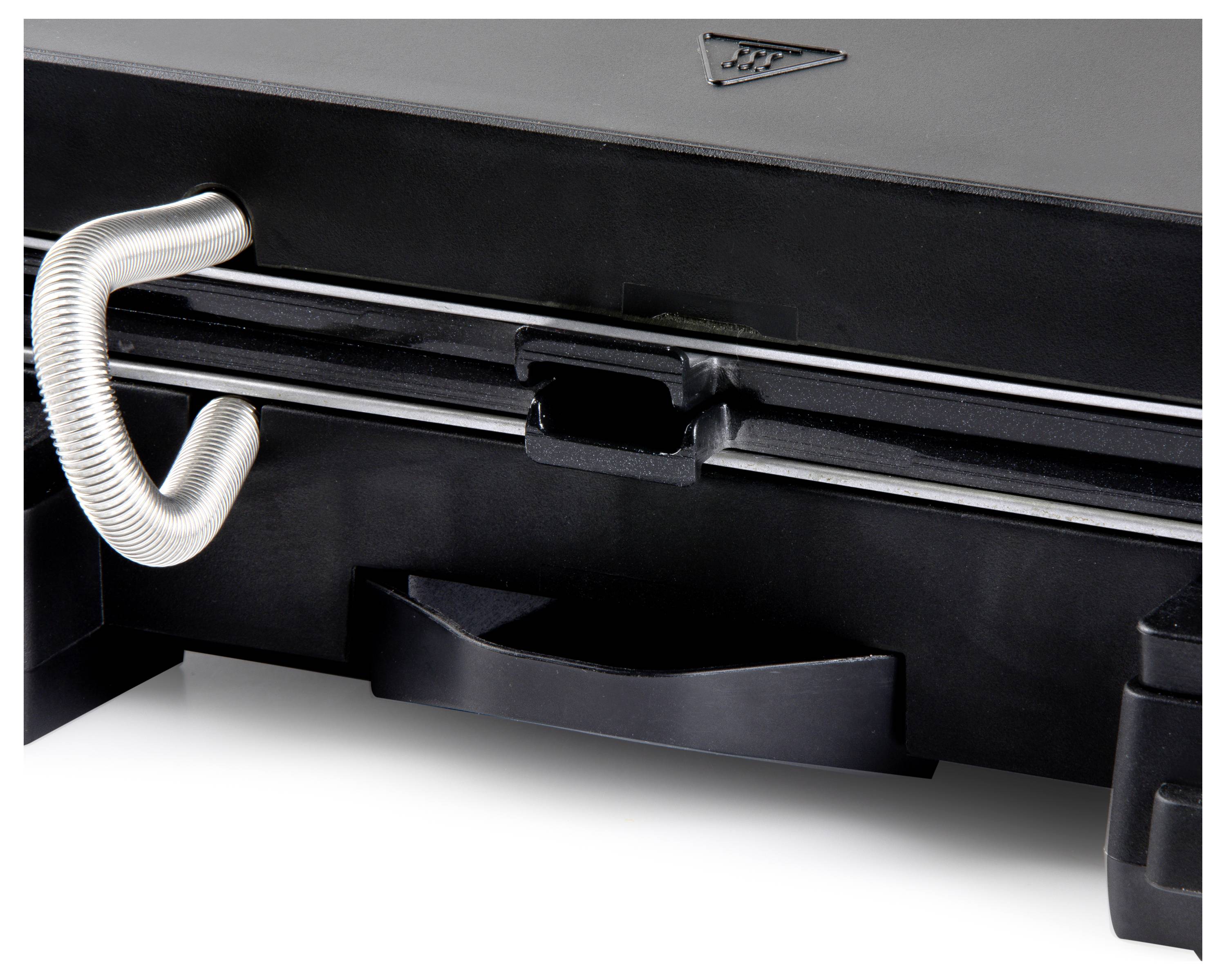 Een zwarte contactgrill met een metalen handgreep en een driehoekig waarschuwingssymbool op de bovenkant is zichtbaar.