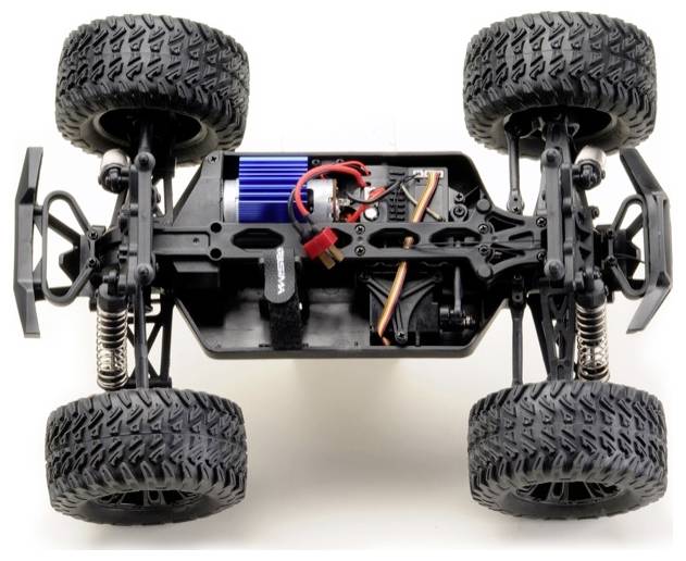 Een modelleer auto chassis met vier grote, robuuste banden, zichtbare veren en interne elektronica, wat het terrein design en constructie benadrukt.