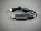 Een zwarte USB-kabel met een rechthoekige aansluiting aan de ene kant en een ronde stekker aan de andere kant, op een grijze achtergrond.