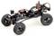 Een modelauto-chassis met vier grote terreinbanden, zichtbare motoren en kabels. Het toont een mechanische opbouw zonder carrosserie.