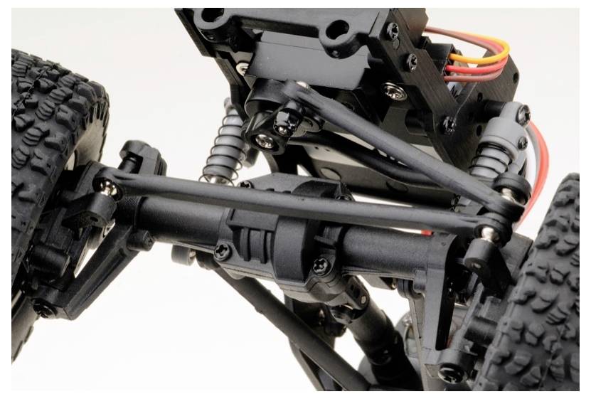 Close-up van een zwart modelauto-chassis met gedetailleerd zicht op de ophanging en schokdempers.