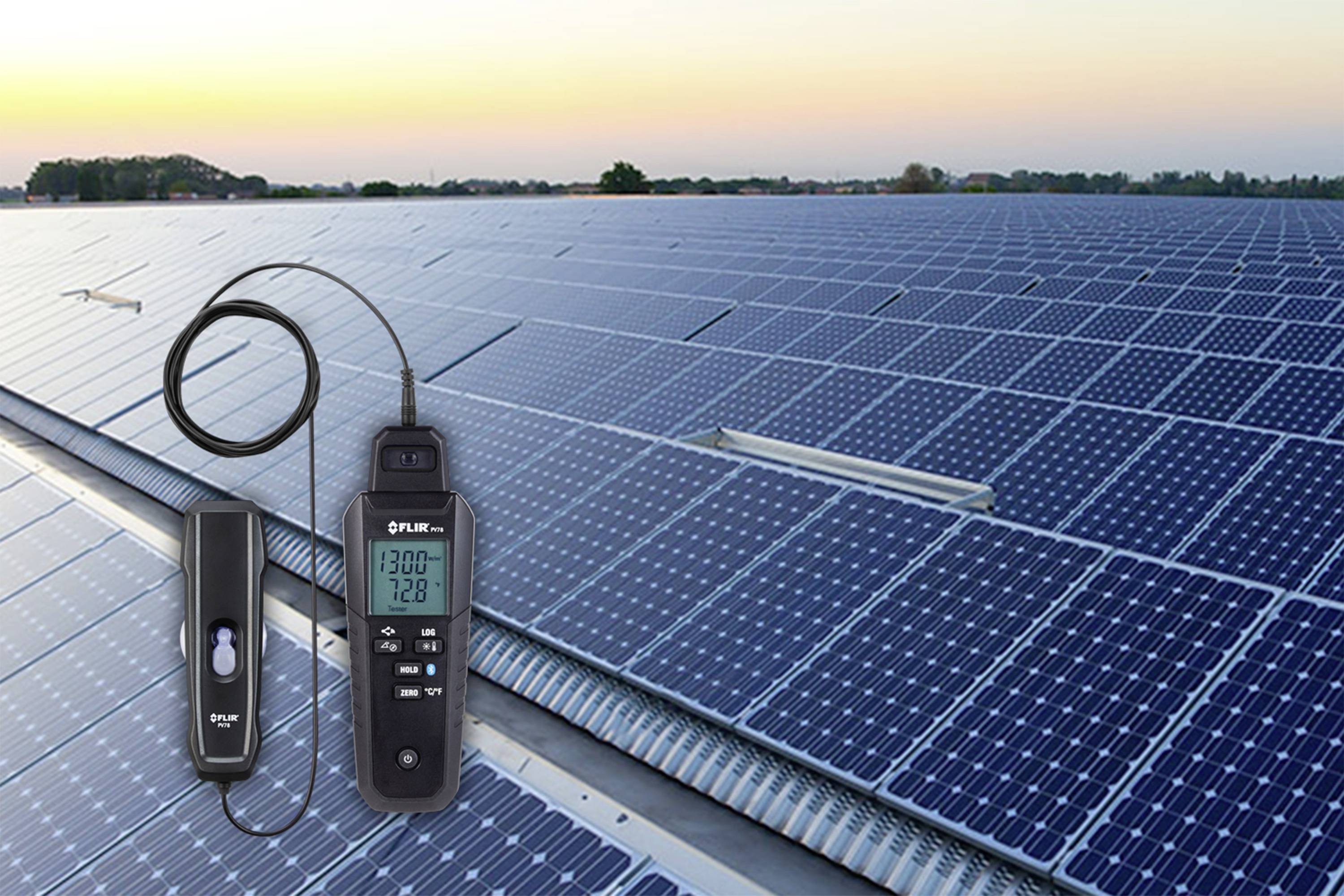 Een zonnepark bij zonsondergang. Op de voorgrond een digitaal meetinstrument met display, gericht op de zonnepanelen.