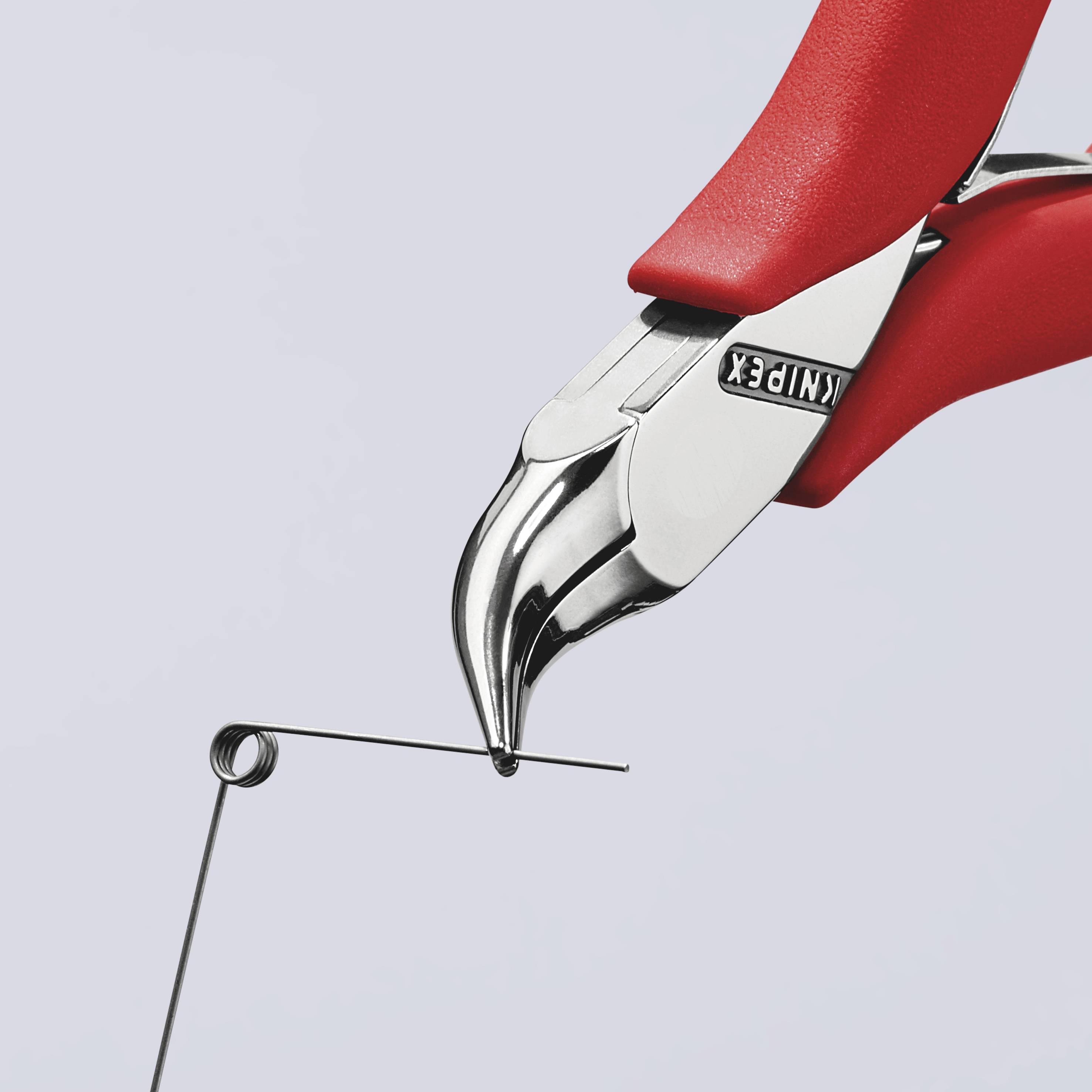 Close-up van een rode tang die een dun metalen stuk vasthoudt. De tang heeft een gebogen metalen kop en ergonomische handgrepen.