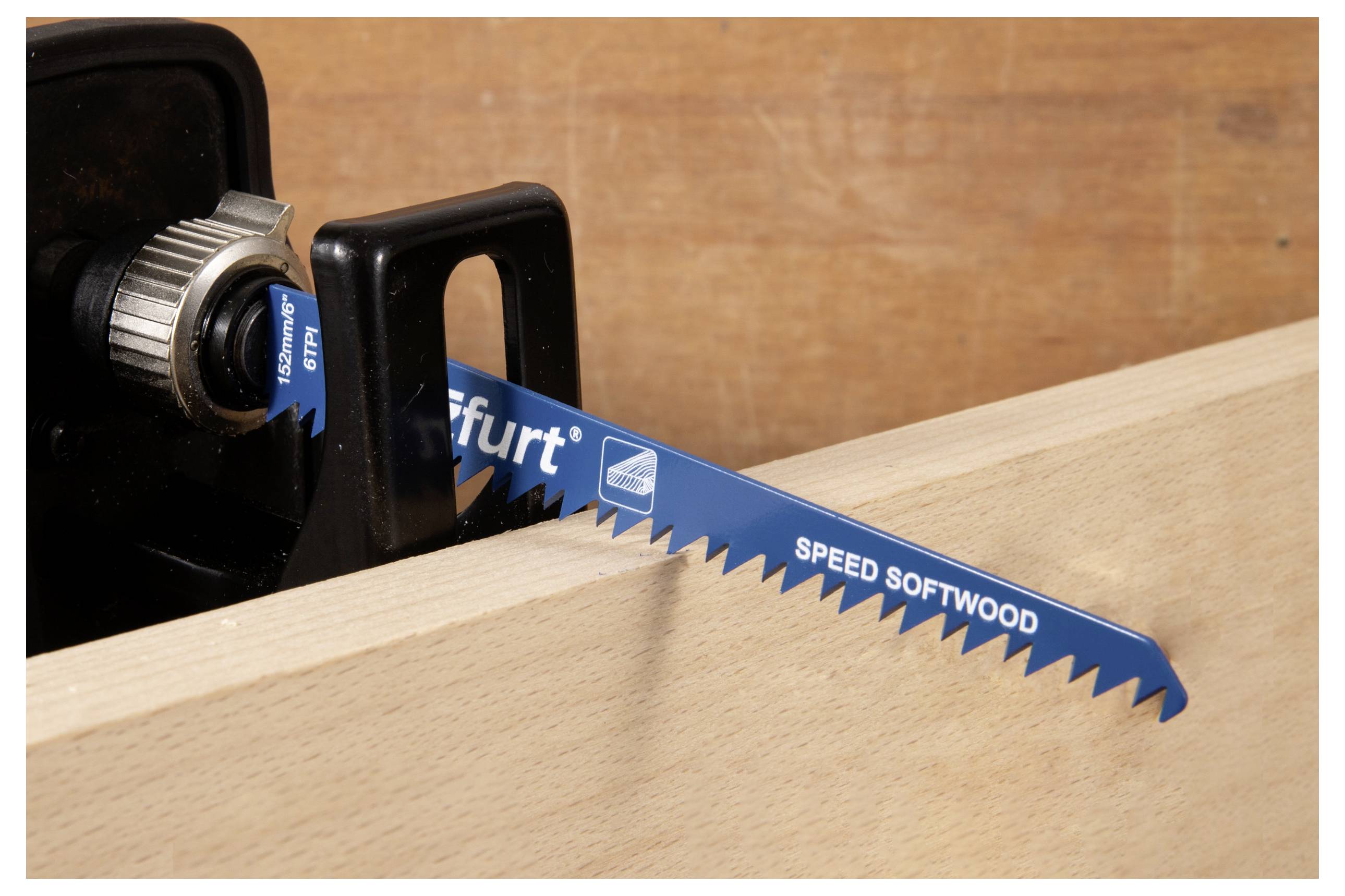 Een blauwe zaagblad gemerkt 'SPEED SOFTWOOD', gemonteerd in een gereedschap, is gepositioneerd boven een houten plank, wat wijst op voorbereiding voor het zagen.