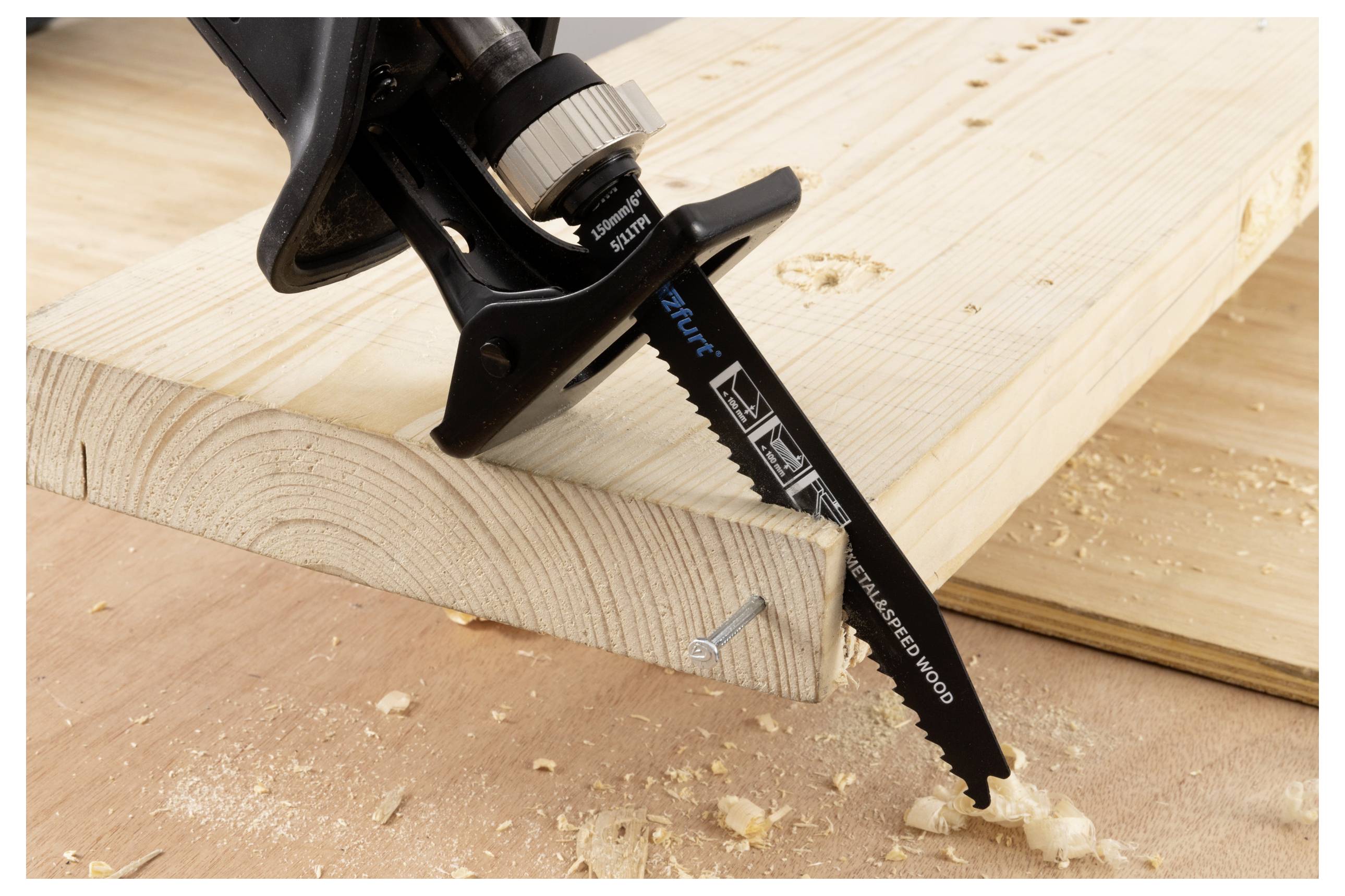Een zaagblad dat door een houten plank snijdt, waarbij houtkrullen achterblijven. De plank wordt vastgezet met een schroef. Het blad is voorzien van specificatielabels.