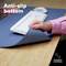 Een hand tilt een bureauonderlegger op met antislip-onderlaag. Ingevoegde tekst: 'Anti-slip onderkant', 'Flexibel materiaal'.