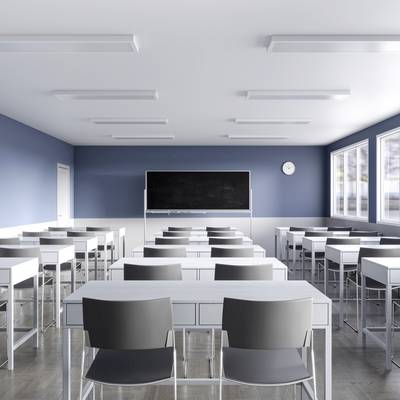 Een leeg, modern klaslokaal met blauwe muren en een groot raam. Er staan verschillende tafels en stoelen, een whiteboard en een klok.