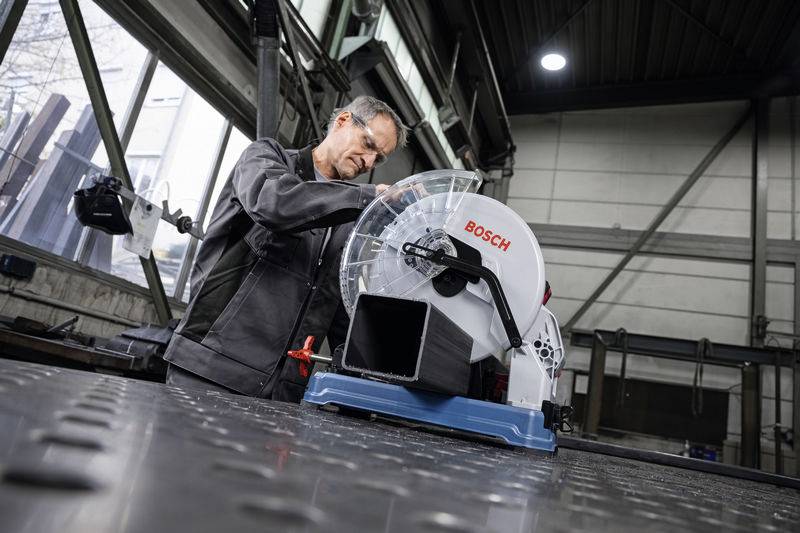 'Een man werkt in een werkplaats aan een Bosch-cirkelzaag, omringd door industriële apparatuur.'