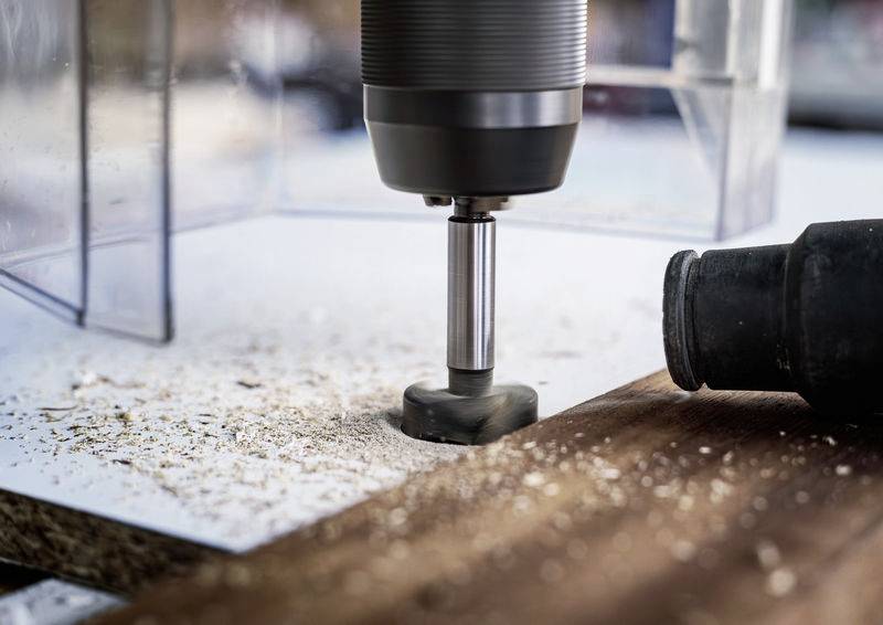 Close-up van een boor die een gat boort in een stuk hout. Houtspaanders verspreiden zich rond de werkplek.