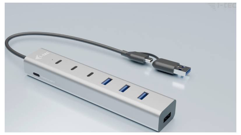 Een zilveren USB-hub met vier USB-poorten en een USB-C-poort, verbonden met een USB-C-kabel, ligt op een lichte achtergrond.