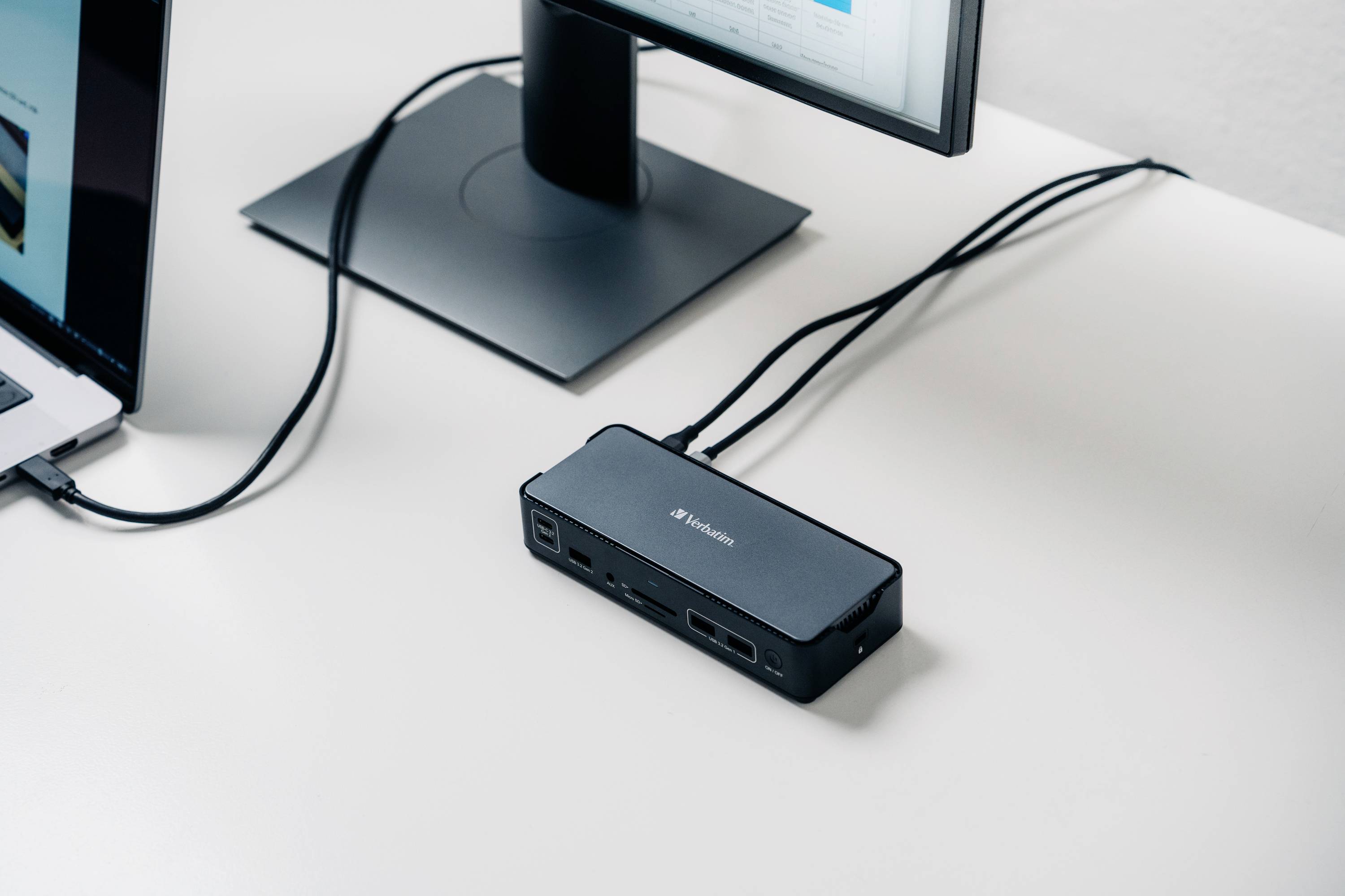 Een USB-hub op een bureau verbindt een laptop en een monitor.