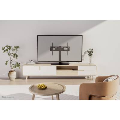 In de woonkamer staat een televisie op een laag houten rek. Ernaast zijn planten sfeervol neergezet in de ruimte.