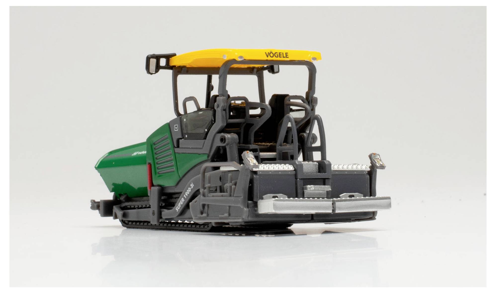 Een model van een Vögele asfaltspreidmachine met een groen en geel kleurenschema, dat zijn gedetailleerde ontwerp en machinale componenten toont.