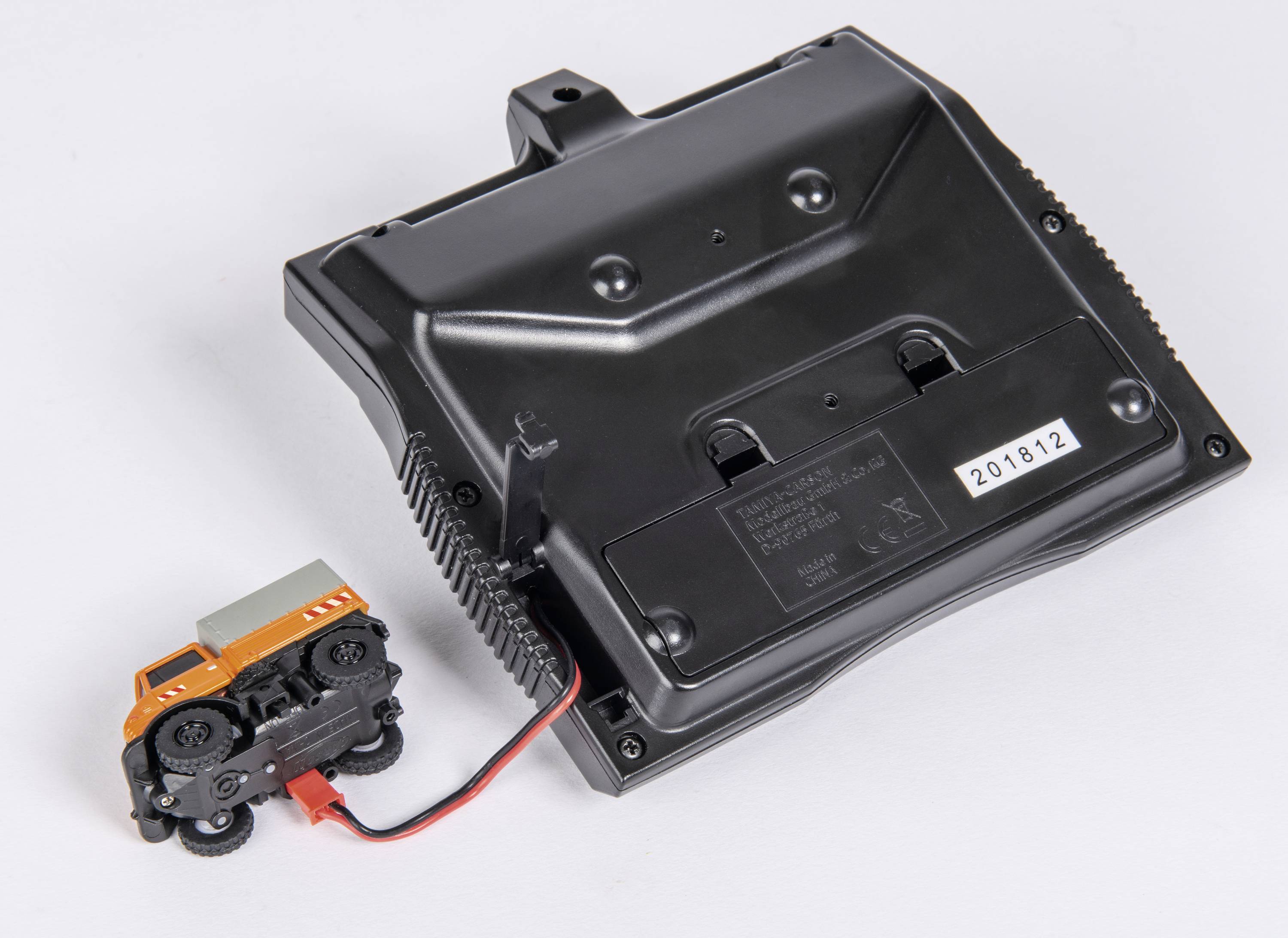 Een kleine modelauto die met een kabel is verbonden met een zwart elektronisch apparaat. Het apparaat heeft een serienummer.