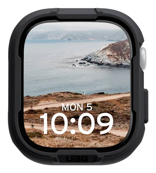 Een smartwatch met zwarte rand toont de tijd '10:09' en de datum als 'MON 5' tegen een kustachtergrond.