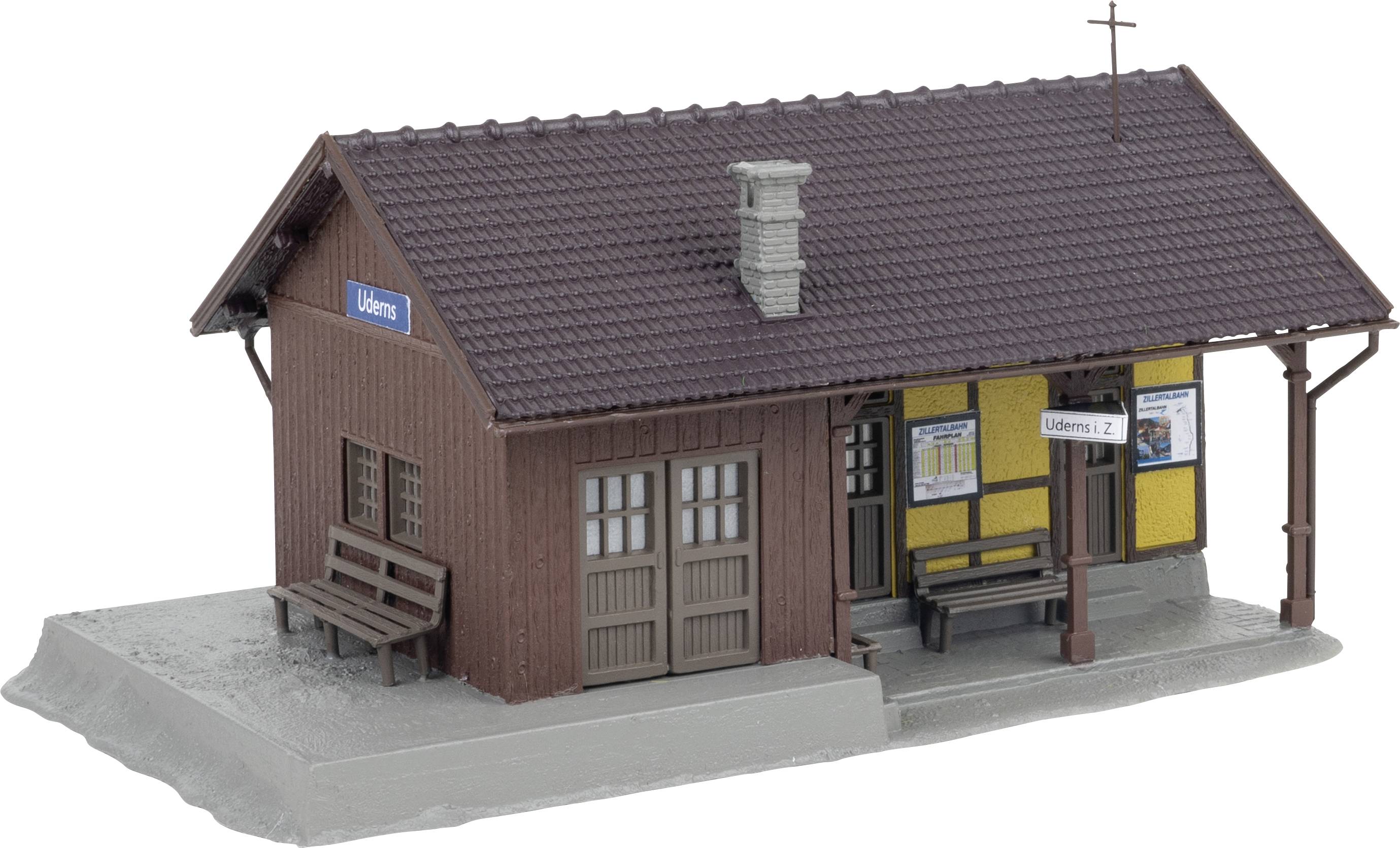 Een klein model van een stationsgebouw met bruine houten bekleding en een bord 'Üdern'. Borden en banken zijn zichtbaar.