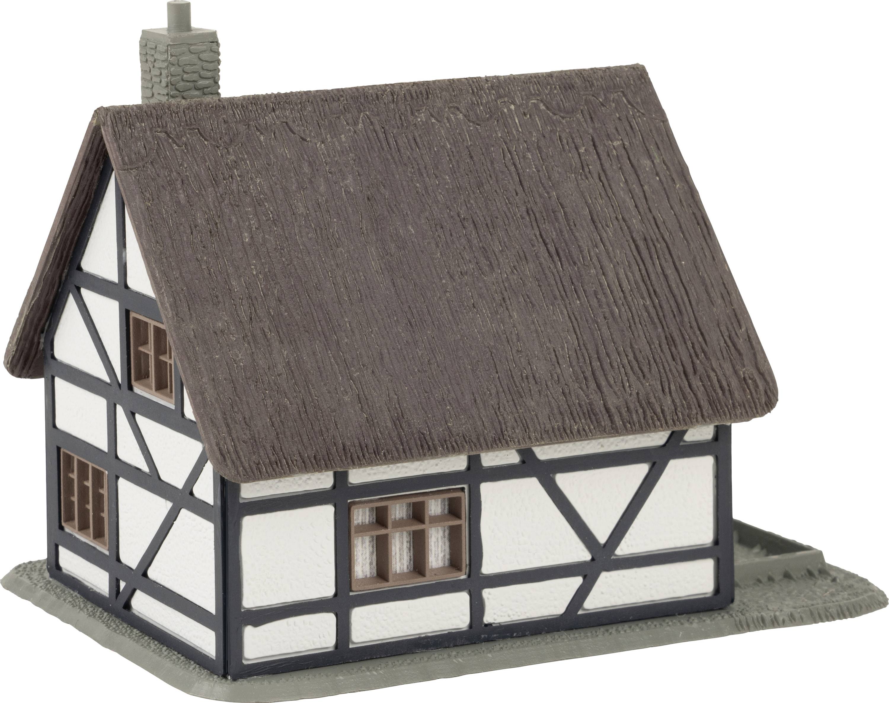 Vakwerkhuismodel met rieten dak en schoorsteen, witte muren met donkere houten balken.