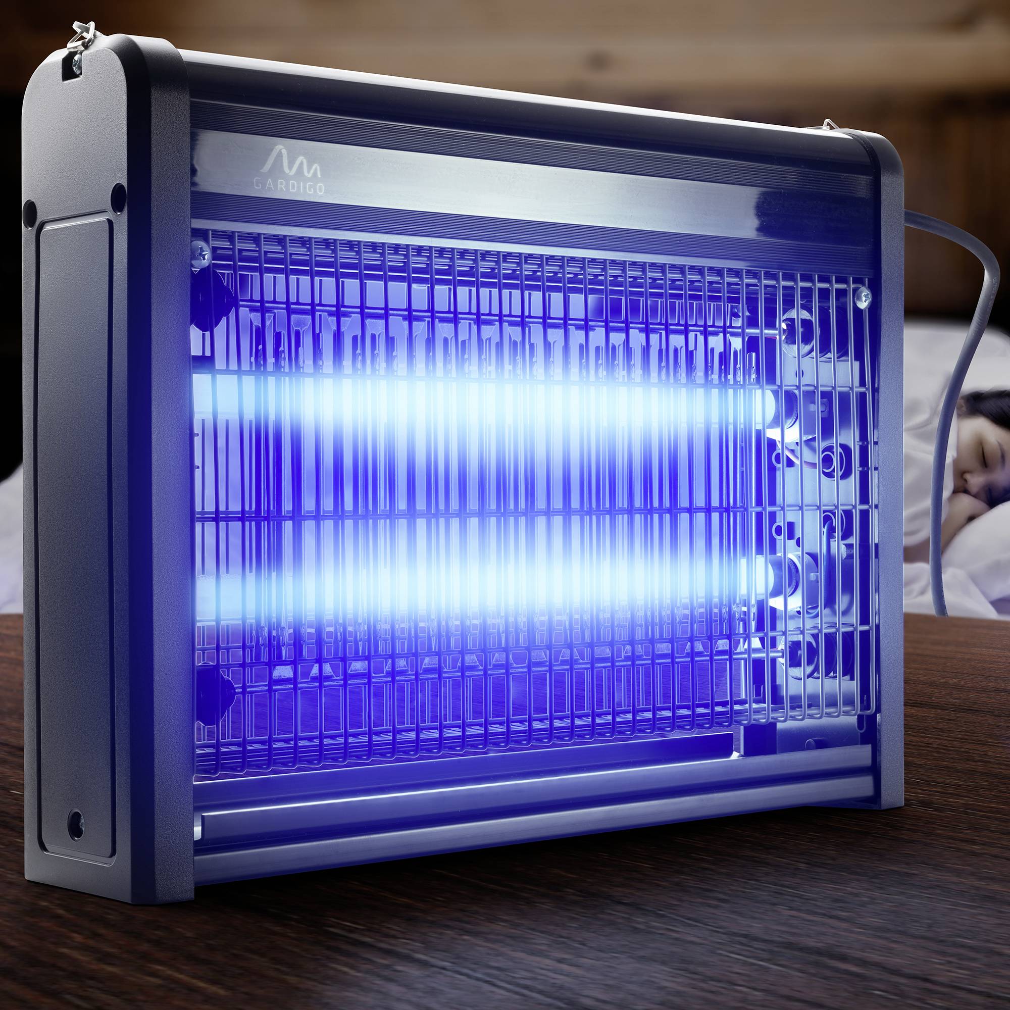 Een elektrische insectenverdelger licht blauw op aan een houten tafel, omringd door lichtrooster die insecten moeten aantrekken.