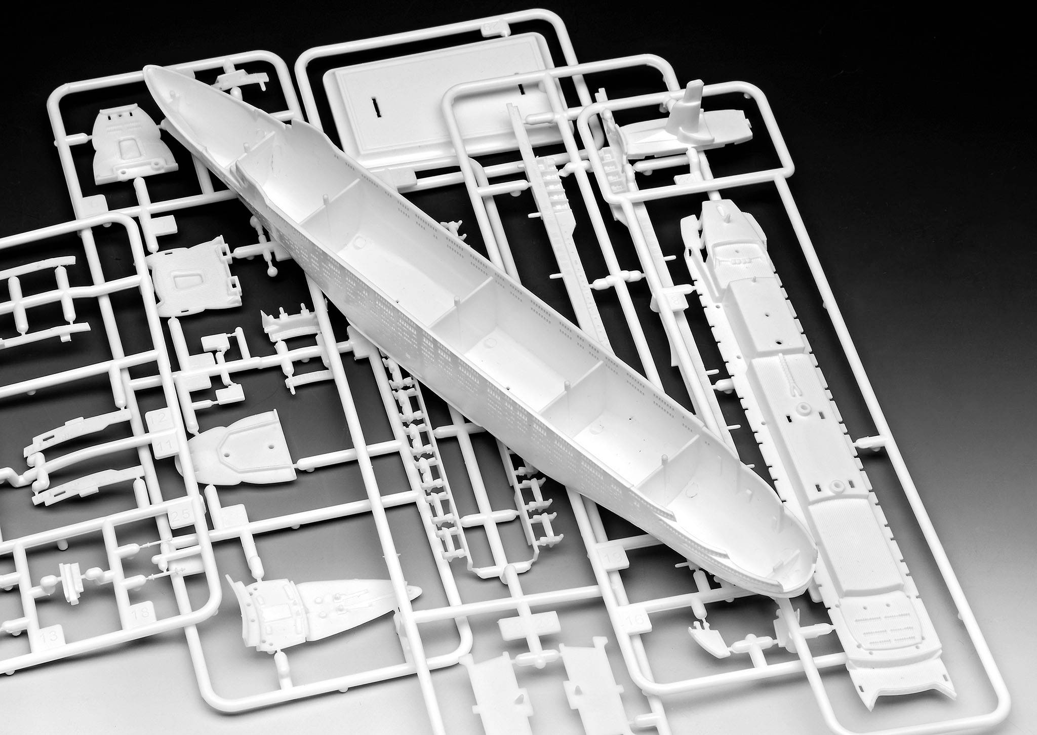 Plastic modelbouwpakket van een schip met afzonderlijke onderdelen op een frame, klaar voor assemblage.