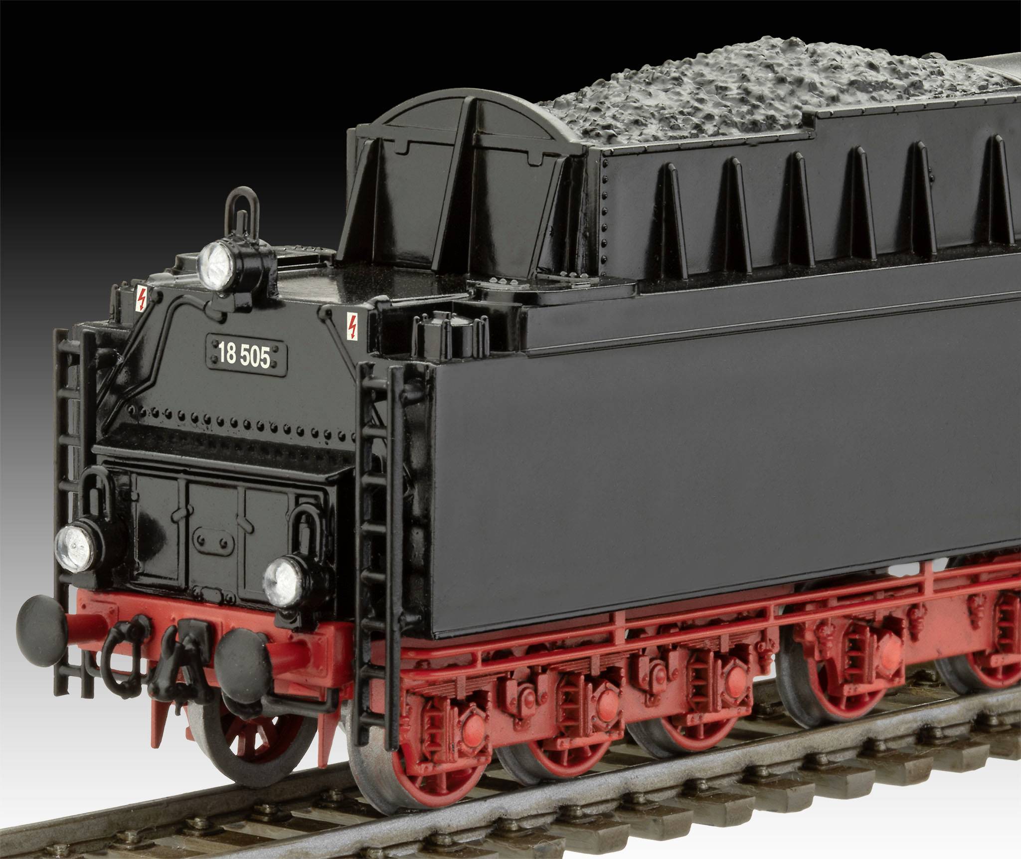 Zwart model van een historische tender-aanhanger van een stoomlocomotief met rode details op een spoor, beladen met steenkool.