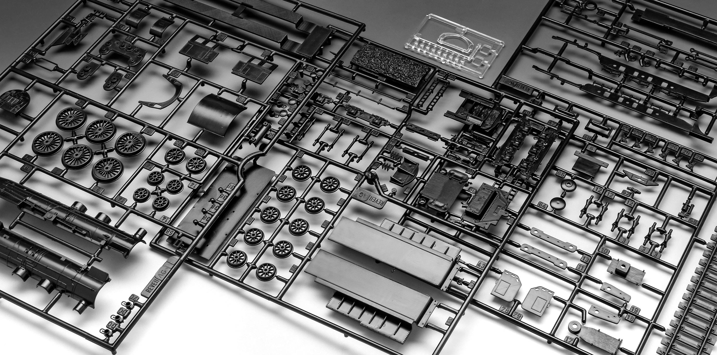 'Zwarte kunststof modelbouwset met verschillende onderdelen en details, klaar om een voertuig in elkaar te zetten.'