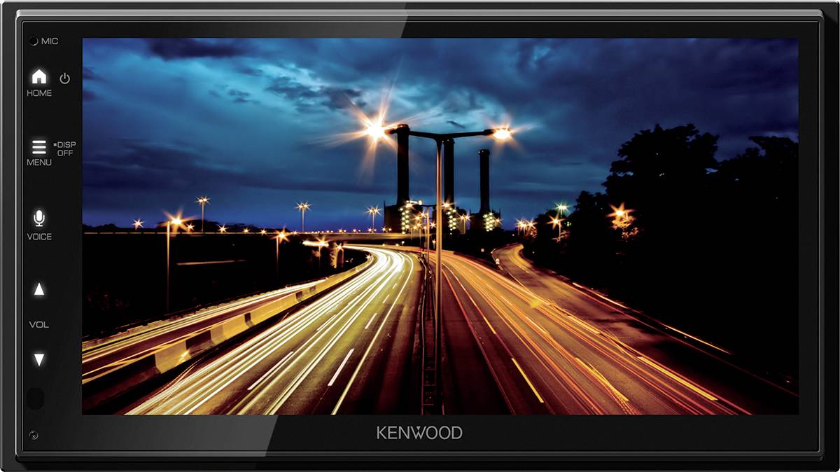 Een nachtelijke snelwegfoto met verlichte wegen, lange lichtsporen van koplampen en een stad op de achtergrond.