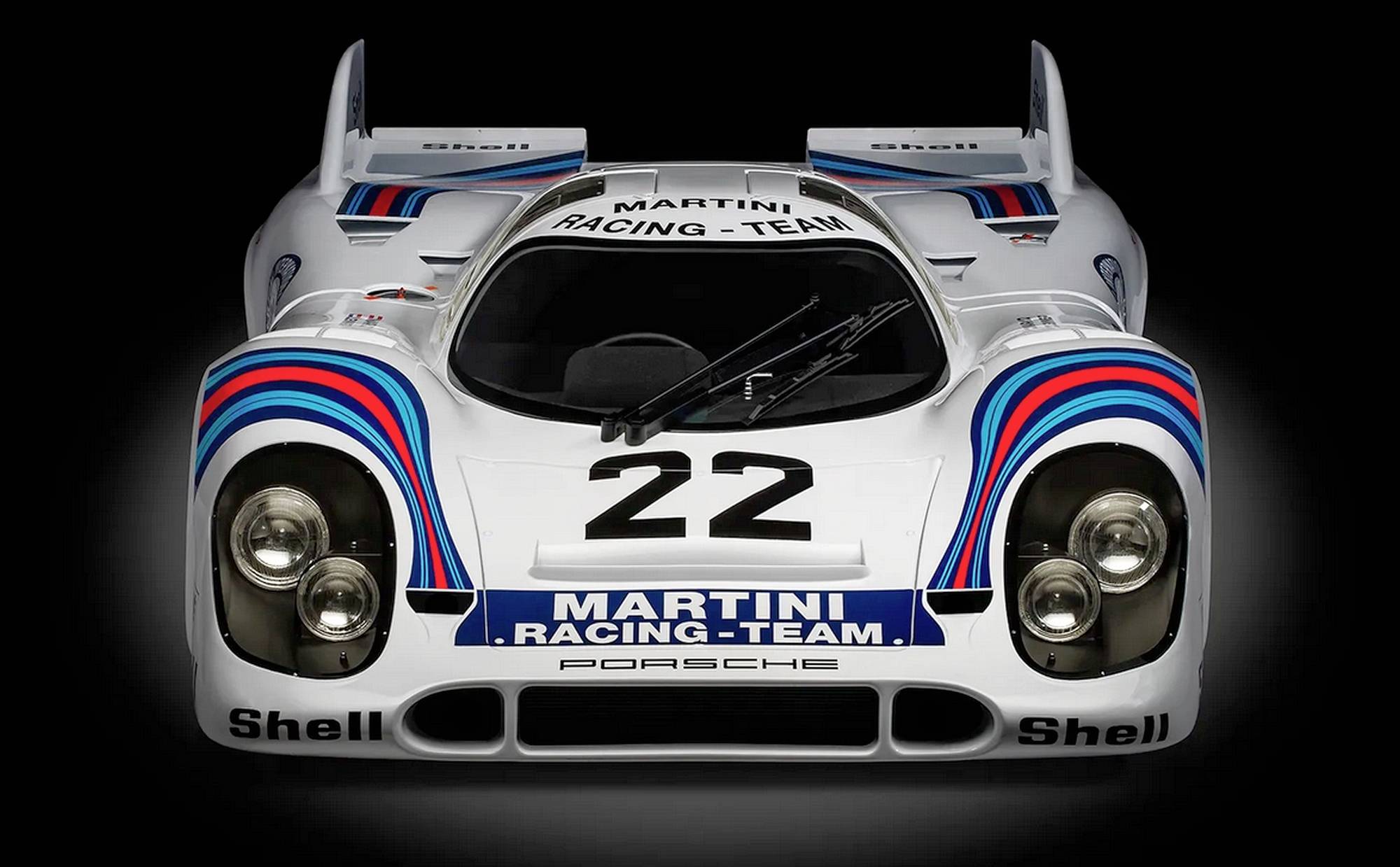 Een historische racewagen met Martini-Racing-design en het nummer 22 op de motorkap, vooraanzicht.